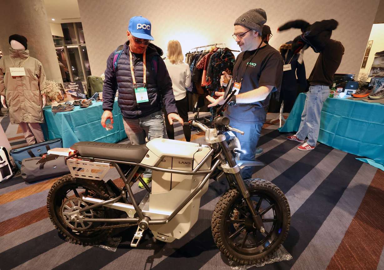 Justin Koski, U.S. Ski and Snowboard Hall of Fame executive director, looks at a LAND electric motorcycle with Evan Painter, LAND head of design, during the Outdoor Retailer media preview at the Hyatt Regency Salt Lake in Salt Lake City on Monday.