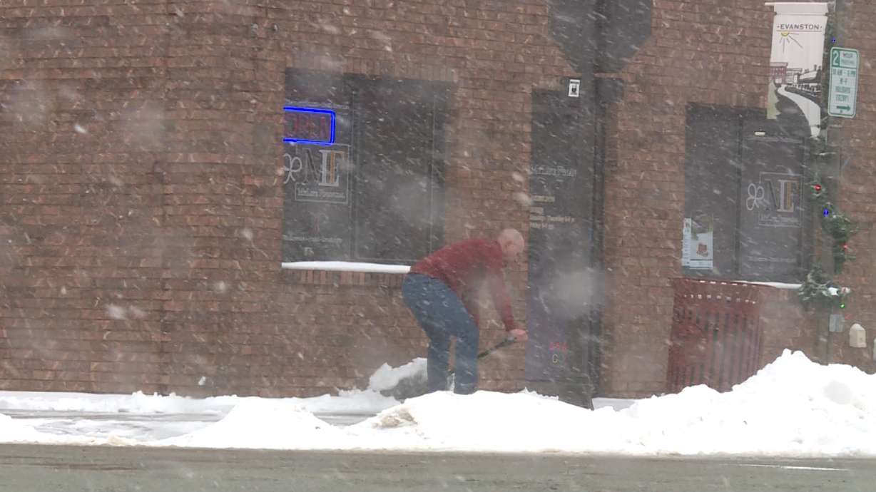 Jared Briggs shovels snow off of the sidewalk in front of his insurance business.