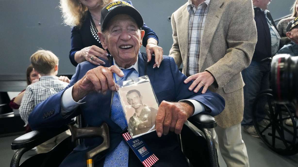 World War II veteran Joseph Eskenazi, who at 104 years and 11 months old is the oldest living veteran to survive the attack on Pearl Harbor, holds a photo of his younger self on Jan. 11, at an event celebrating his upcoming 105th birthday at the National World War II Museum in New Orleans.