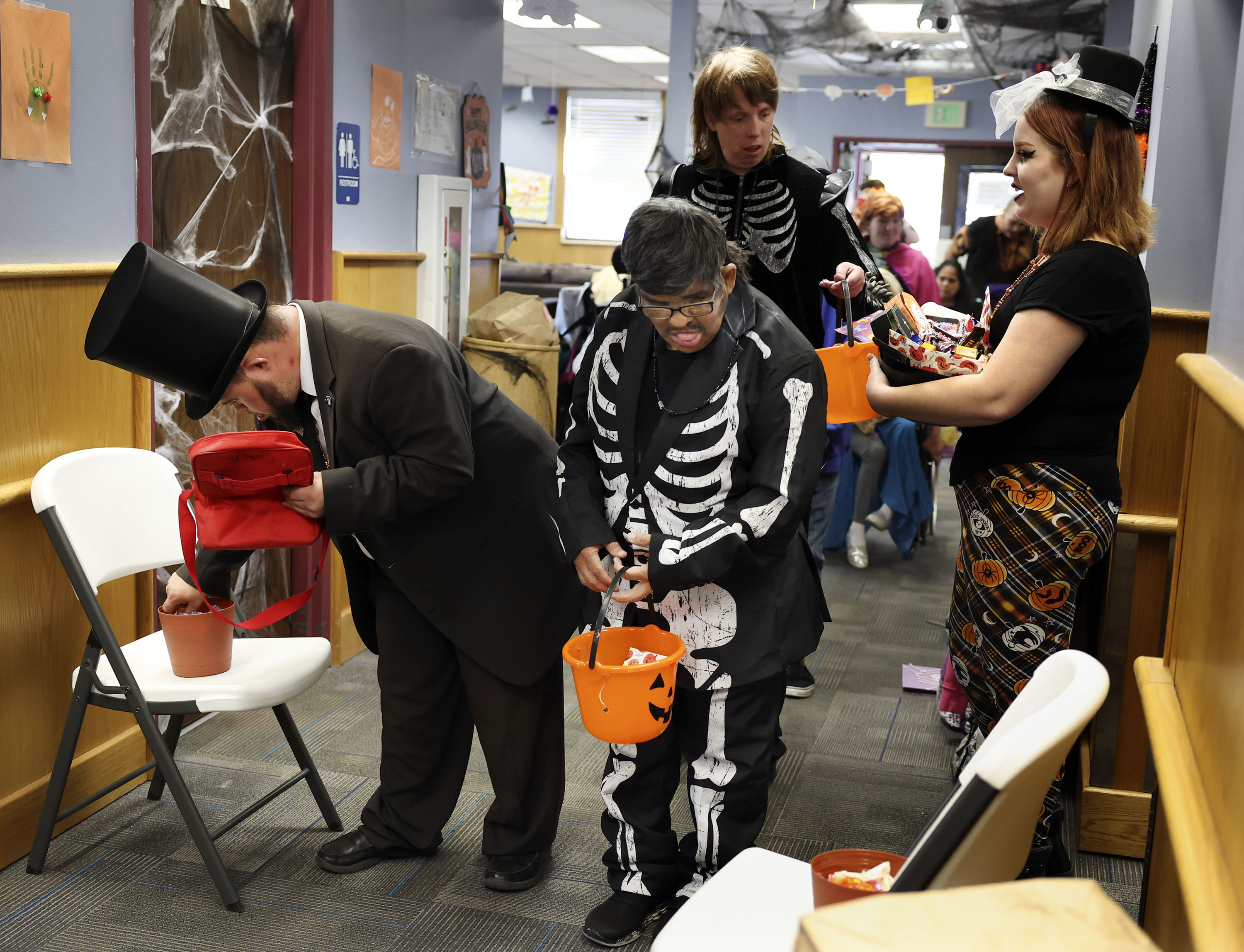 Cade, left, dressed as Abraham Lincoln, Jr., and Rudy and Ryan, dressed as skeletons, get Halloween candy from Valerie Trull, right, at Together We Shine in Ogden on Oct. 31, 2022. A proposed resolution seeks to have Halloween events held on the last Friday of every October.