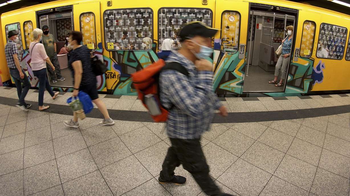 People wear face masks as they leave and board a subway train in Berlin, Germany, on June 23, 2020. Germany’s health minister says the country will soon drop a mask mandate in long-distance trains and buses, one of the country’s last remaining COVID-19 restrictions.
