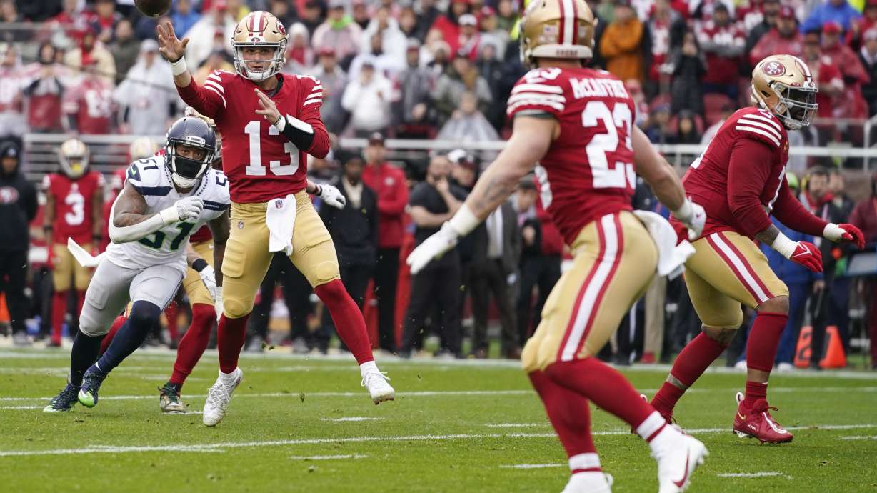 San Francisco 49ers quarterback Brock Purdy (13) throws touchdown pass to running back Christian McCaffrey (23) in front of Seattle Seahawks linebacker Bruce Irvin (51) during the first half of an NFL wild card playoff football game in Santa Clara, Calif., Saturday, Jan. 14, 2023.
