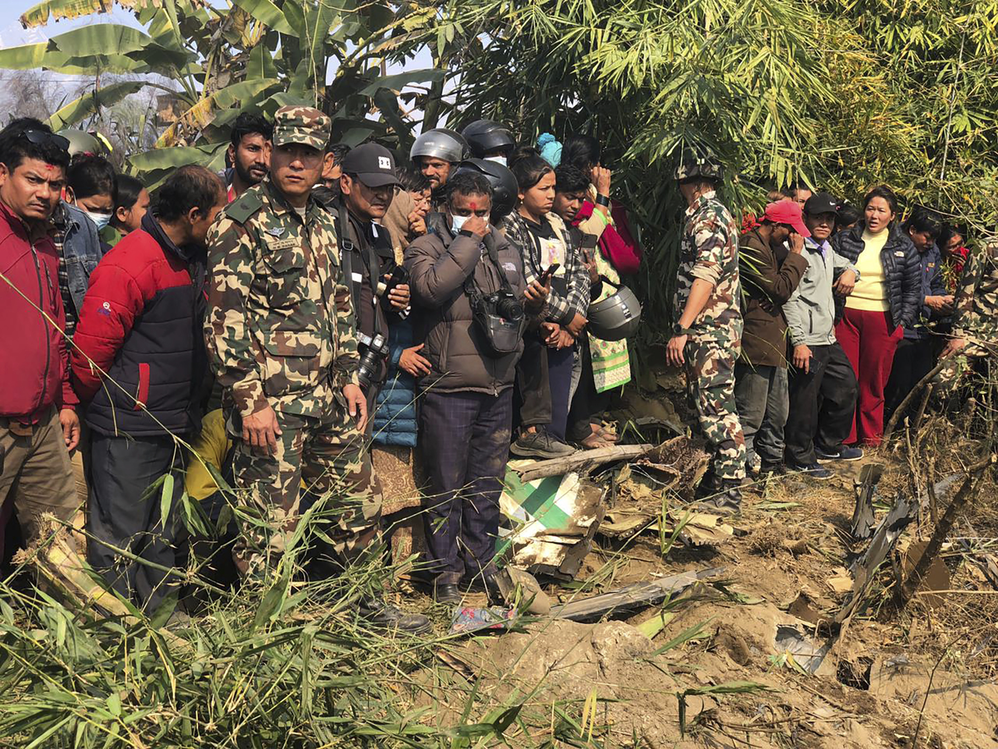 Locals watch the wreckage of a passenger plane in Pokhara, Nepal, Sunday. A passenger plane with 72 people on board has crashed near Pokhara International Airport in Nepal, the daily newspaper Kathmandu Post reports.