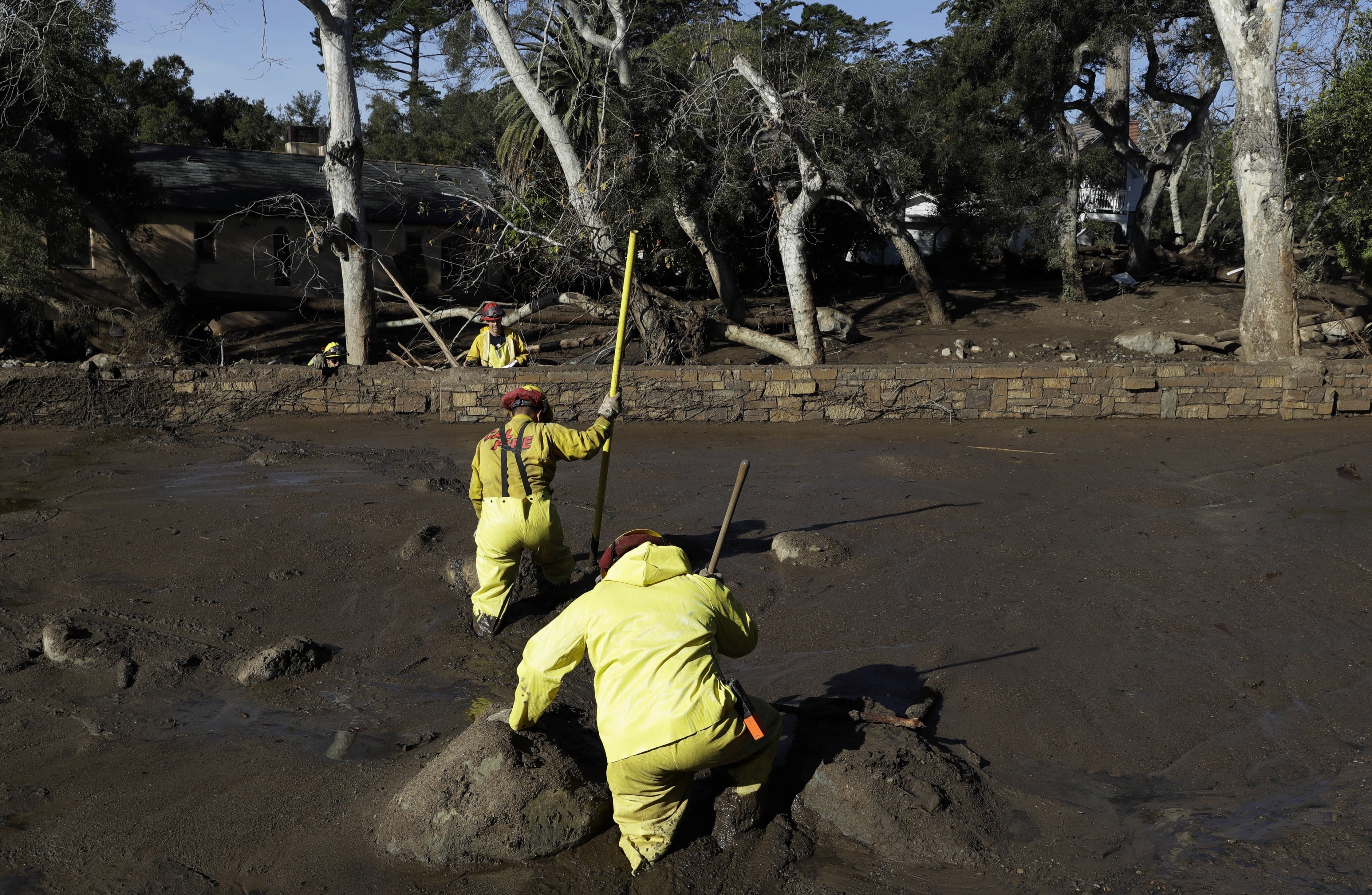 A Cal Fire search and rescue crew walks through mud near homes damaged by storms in Montecito, Calif., Jan. 12, 2018. Experts say California has learned important lessons from the Montecito tragedy, and the state has more tools to pinpoint the hot spots and more basins and nets are in place to capture the falling debris before it hits homes.