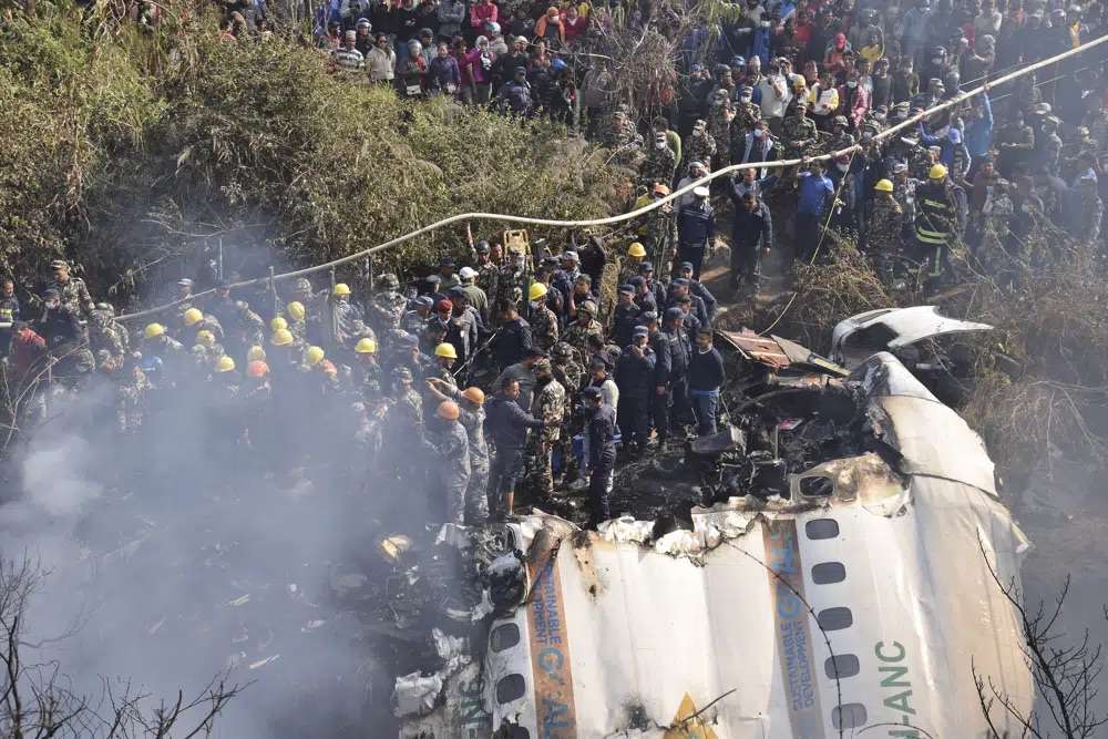Nepalese rescue workers and civilians gather around the wreckage of a passenger plane that crashed in Pokhara, Nepal, Sunday. Authorities in Nepal said 68 people have been confirmed dead after a regional passenger plane with 72 aboard crashed.