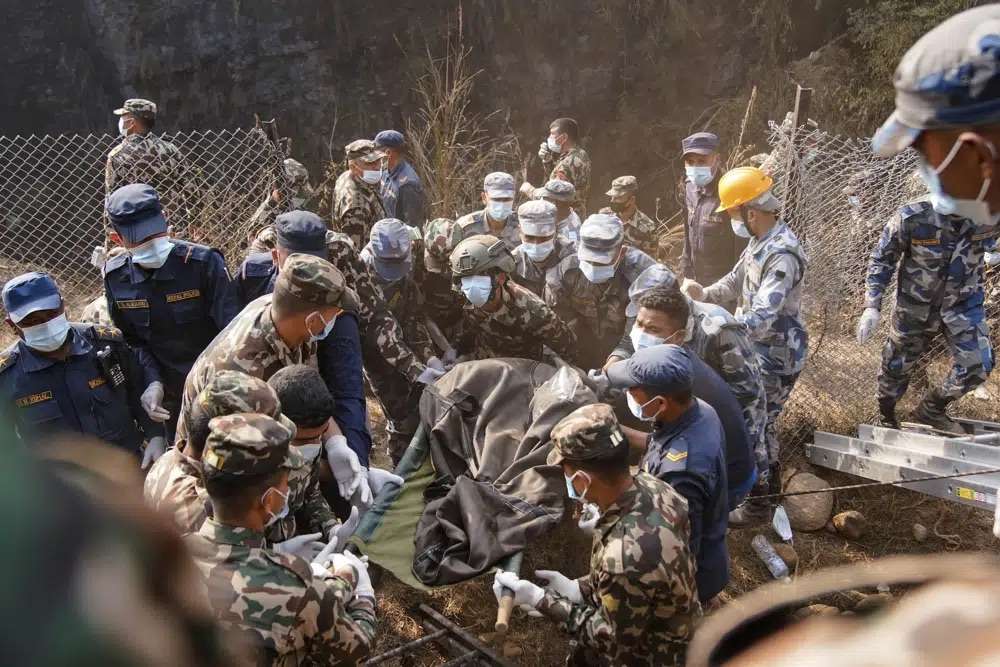 Rescue workers recover the body of a victim of a passenger plane that crashed in Pokhara, Nepal, Sunday. A plane making a 27-minute flight to a Nepal tourist town crashed into a gorge Sunday while attempting to land at a newly opened airport, killing at least 68 of the 72 people aboard.