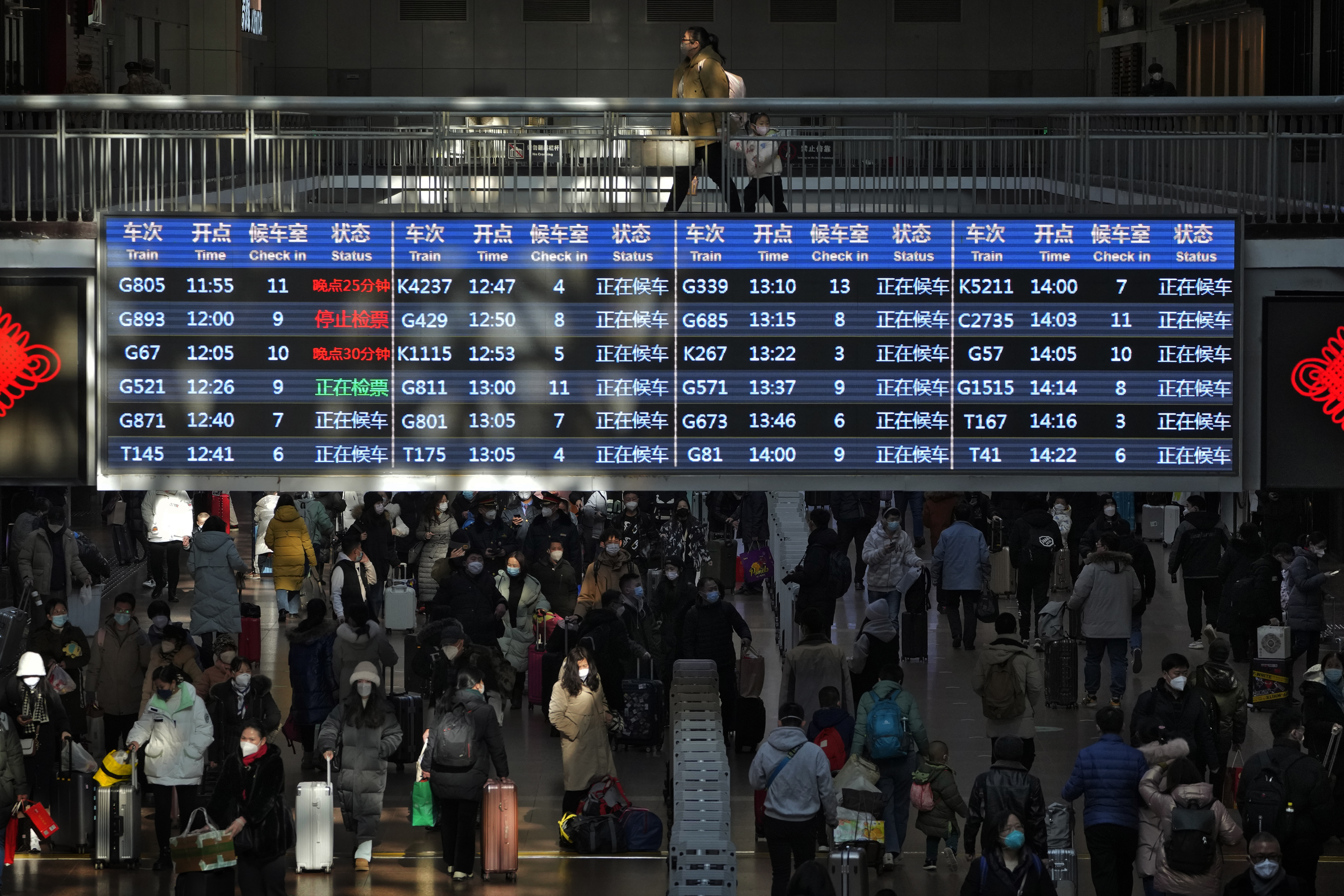 Travelers walk by a trains departure board in Beijing on Sunday. China has announced its first overall population decline in recent years. 