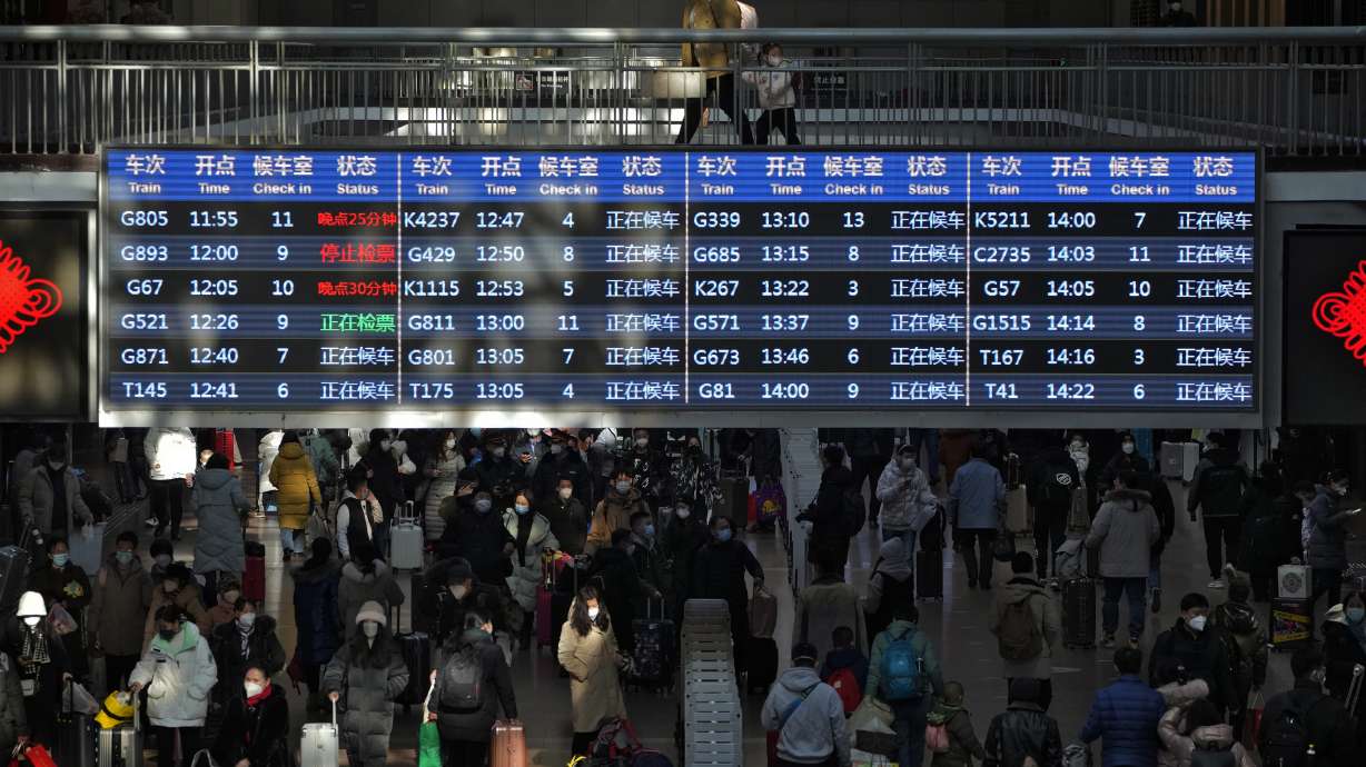 Travelers walk by a trains departure board in Beijing on Sunday. China has announced its first overall population decline in recent years.