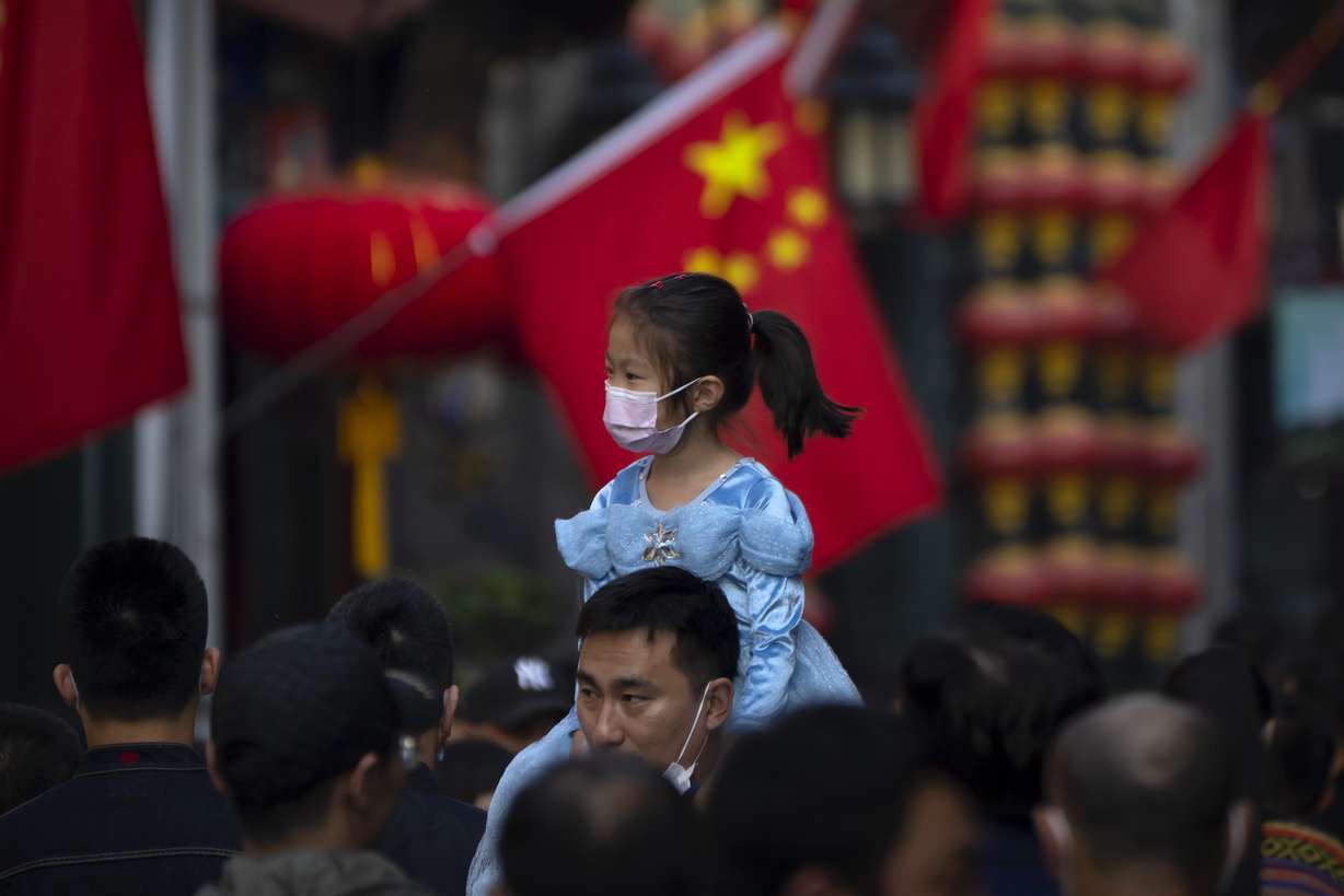 A girl wearing a face mask rides on a man's shoulders as they walk along a tourist shopping street in Beijing on Oct. 7, 2022.