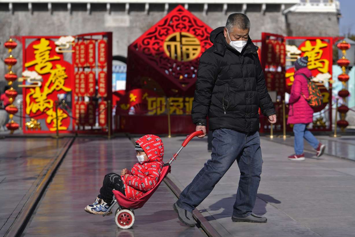 A man pulls a child past a Lunar New Year decoration on display at the Qianmen pedestrian shopping street, a popular tourist spot in Beijing, Tuesday.