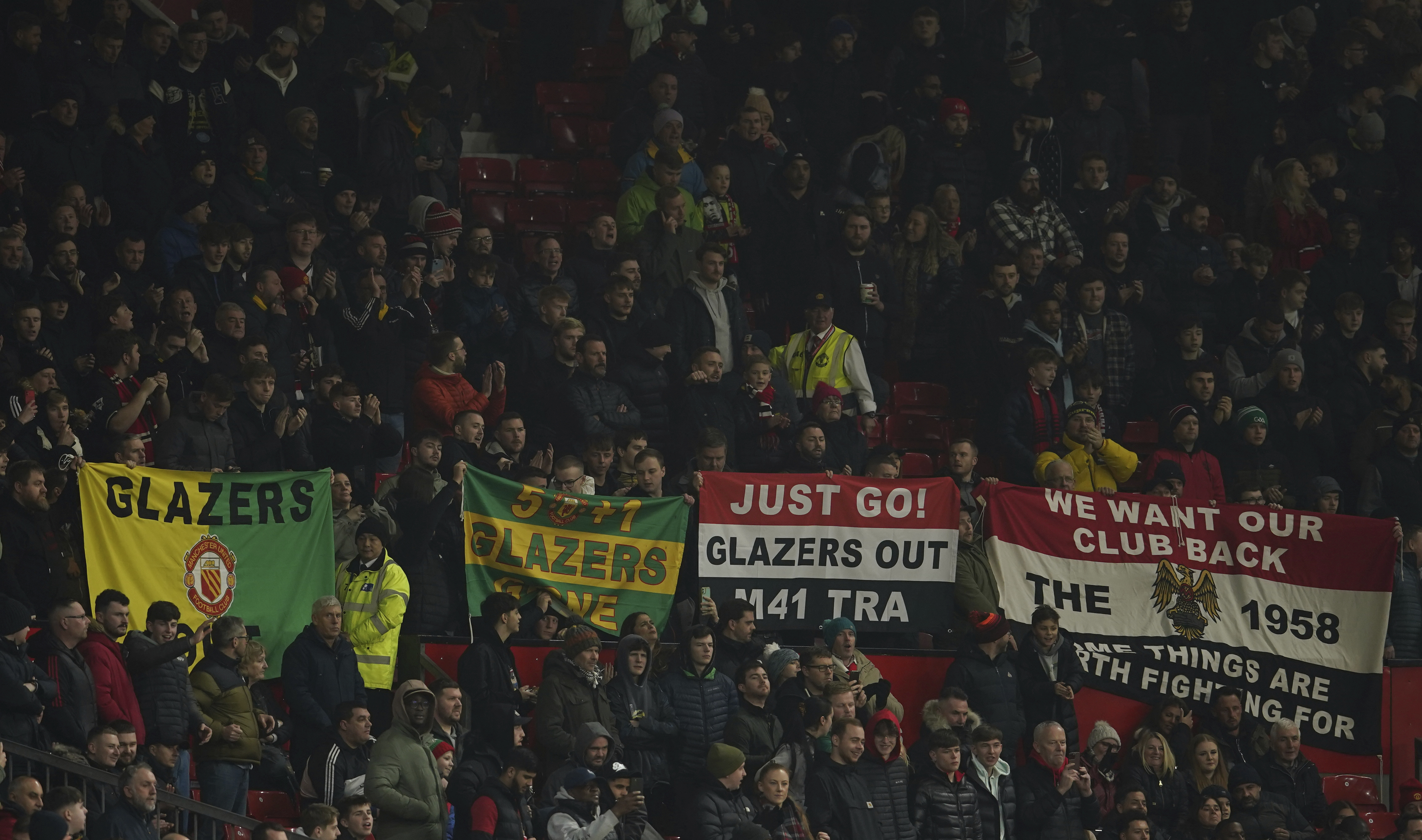 Manchester United fans hold up banners against the current owners of the club the Glazers, just ahead of the start of the English League Cup 4th round soccer match between Manchester United and Burnley, at Old Trafford in Manchester, England Wednesday, Dec. 21, 2022. 