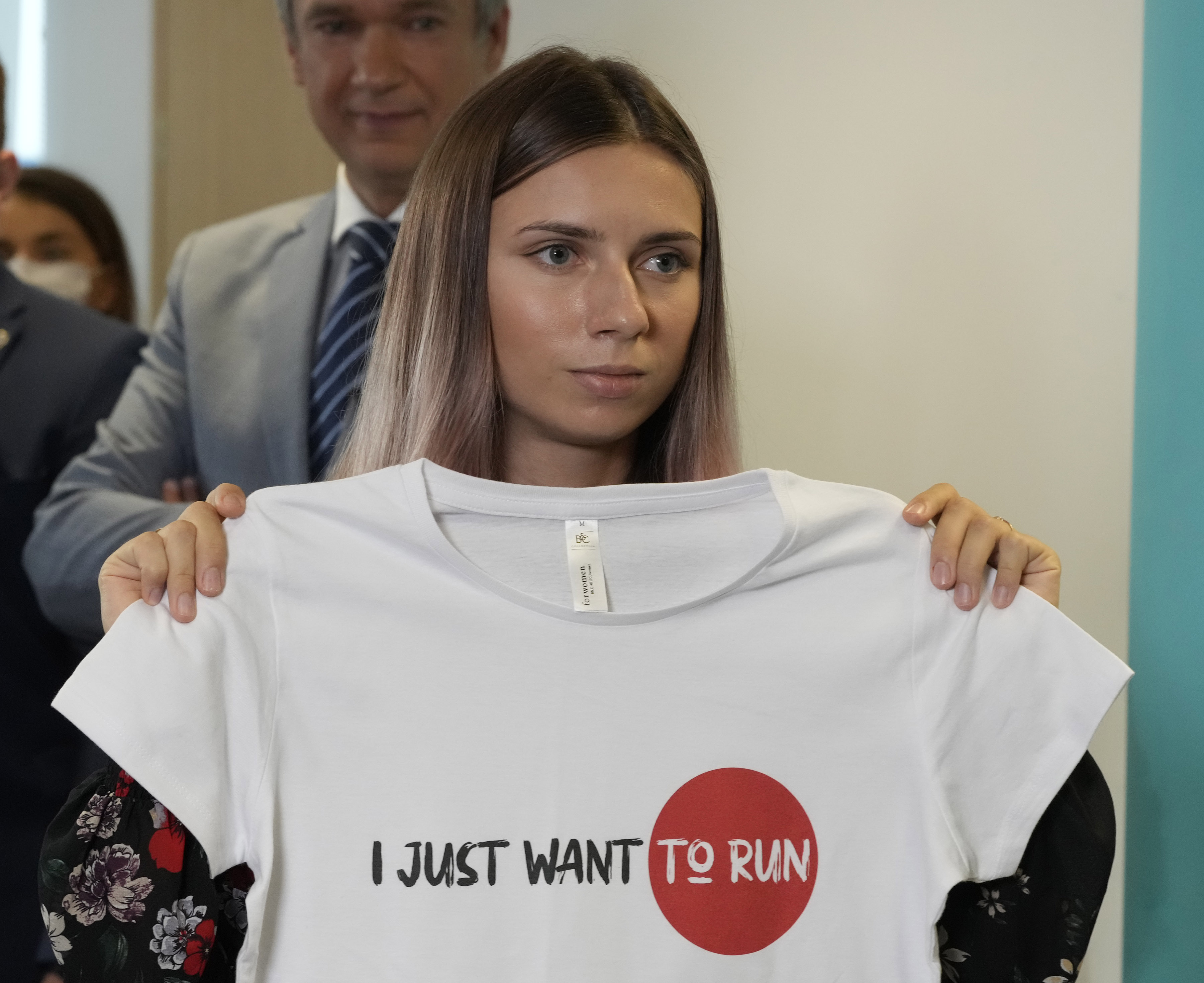 FILE - Belarusian Olympic sprinter Krystsina Tsimanouskaya, who arrived in Poland fearing reprisals at home after criticizing her coaches at the Tokyo Games, holds up an Olympic-related T-shirt with the slogan "I Just Want to Run" after her news conference in Warsaw, Poland, Thursday, Aug. 5, 2021. The Belarusian track coach who tried to force the sprinter out of the Tokyo Olympics and back to Belarus after she was critical of the team has been charged with breaching the sport's integrity standards. The Athletics Integrity Unit announced the charges against Yury Maisevich on Thursday, Jan. 19, 2023. 