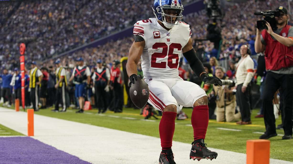New York Giants' Saquon Barkley runs for a touchdown during the first half of an NFL wild card football game against the Minnesota Vikings Sunday, Jan. 15, 2023, in Minneapolis.