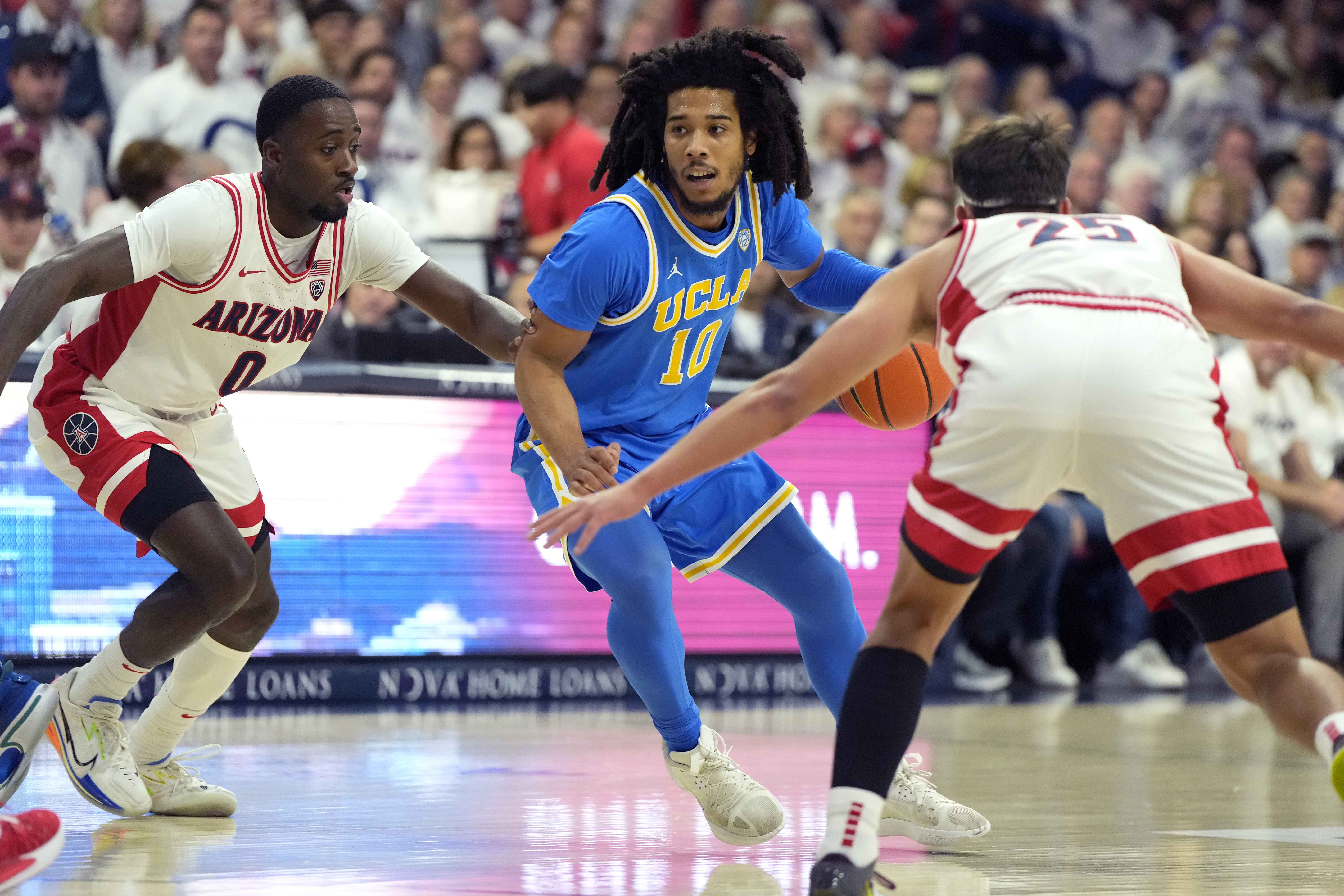 UCLA guard Tyger Campbell drives between Arizona guards Courtney Ramey (0) and Kerr Kriisa during an NCAA college basketball game, Saturday, Jan. 21, 2023, in Tucson, Ariz. 