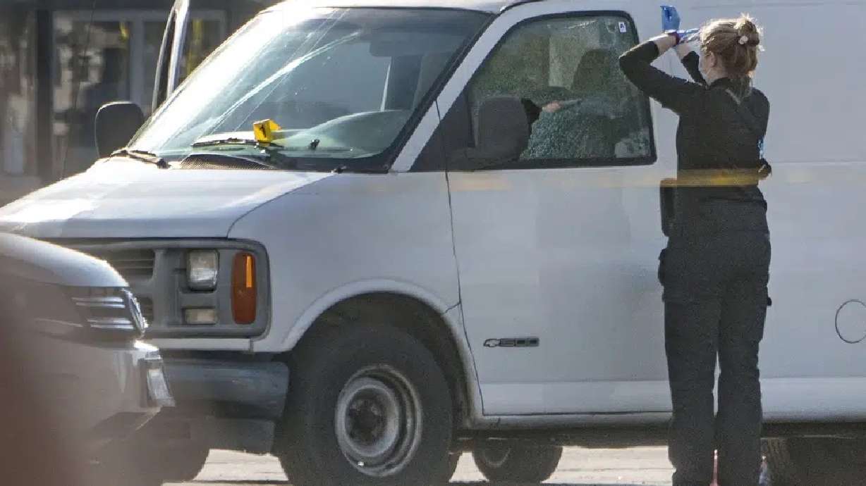 A forensic photographer gets ready to take pictures of a van's window and its contents in Torrance, Calif., Sunday.