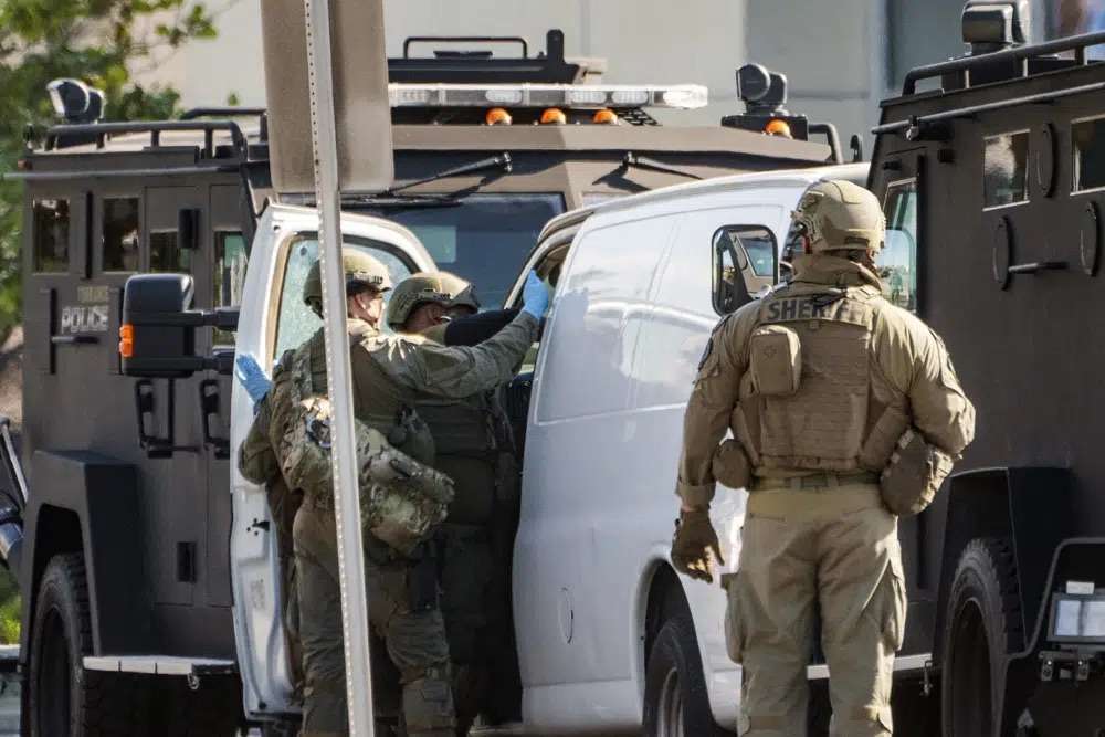 Members of a SWAT team enter a van and look through its contents in Torrance Calif., Sunday. An hours-long manhunt led police to surround and enter the van. Authorities say the suspect in a California dance club shooting that left multiple people dead, shot and killed himself.