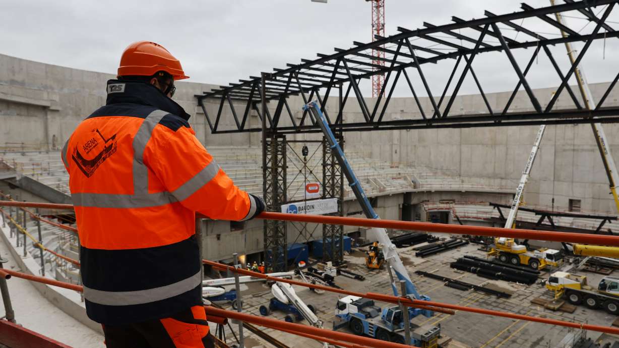 A worker looks at the Paris2024 Olympics Porte de la Chapelle Arena building site Monday, Jan. 23, 2023 in Paris. The olympic venue will host the badminton and rhythmic gymnastics event and para badminton and para powerlifting with a capacity of 6,700 to 7,000 spectators.