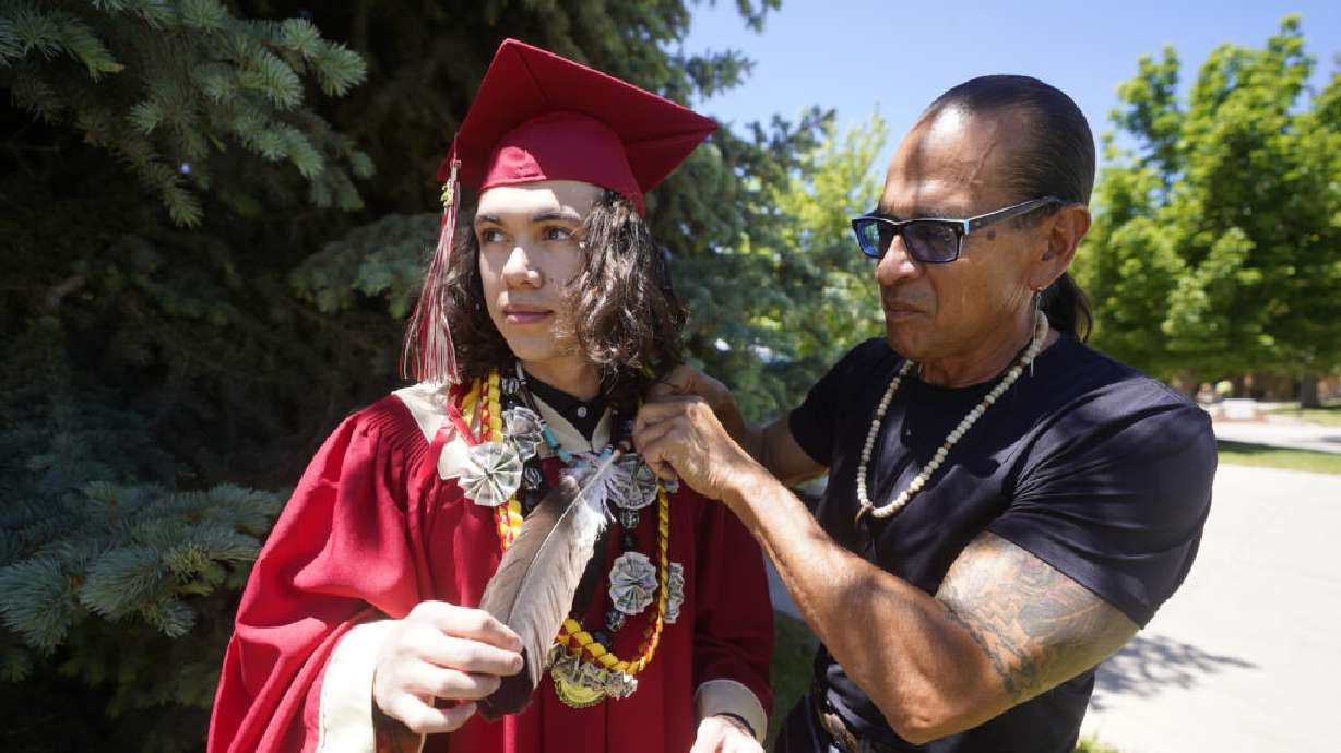 Hoksila Lakota, right, ties an eagle feather to Elijah Wiggins before his graduation from Cedar City High School on May 25, 2022, in Cedar City. Wiggins crossed the stage to accept his diploma wearing the eagle feather that his uncle, Lakota, had gifted him ahead of the ceremony to celebrate his graduation.