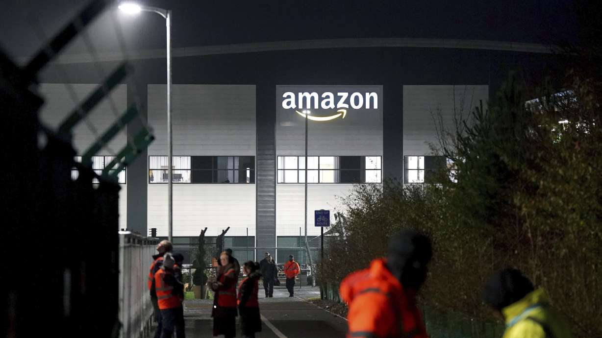 Members of the Amazon security keep an eye on members of the GMB union picketing outside the Amazon fulfilment centre as Amazon workers stage their first ever strike in the UK in a dispute over pay, in Coventry, England, Wednesday, Jan. 25, 2023.