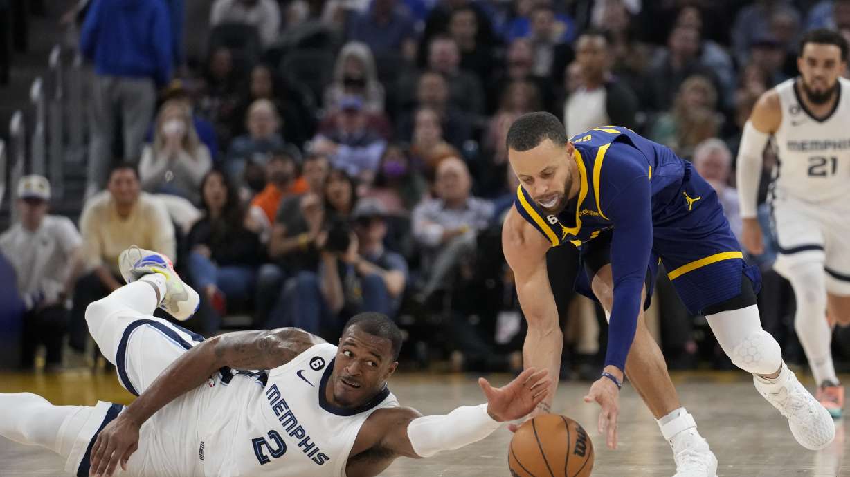 Memphis Grizzlies forward Xavier Tillman Sr., left, and Golden State Warriors guard Stephen Curry compete for possession of the ball during the first half of an NBA basketball game in San Francisco, Wednesday, Jan. 25, 2023.
