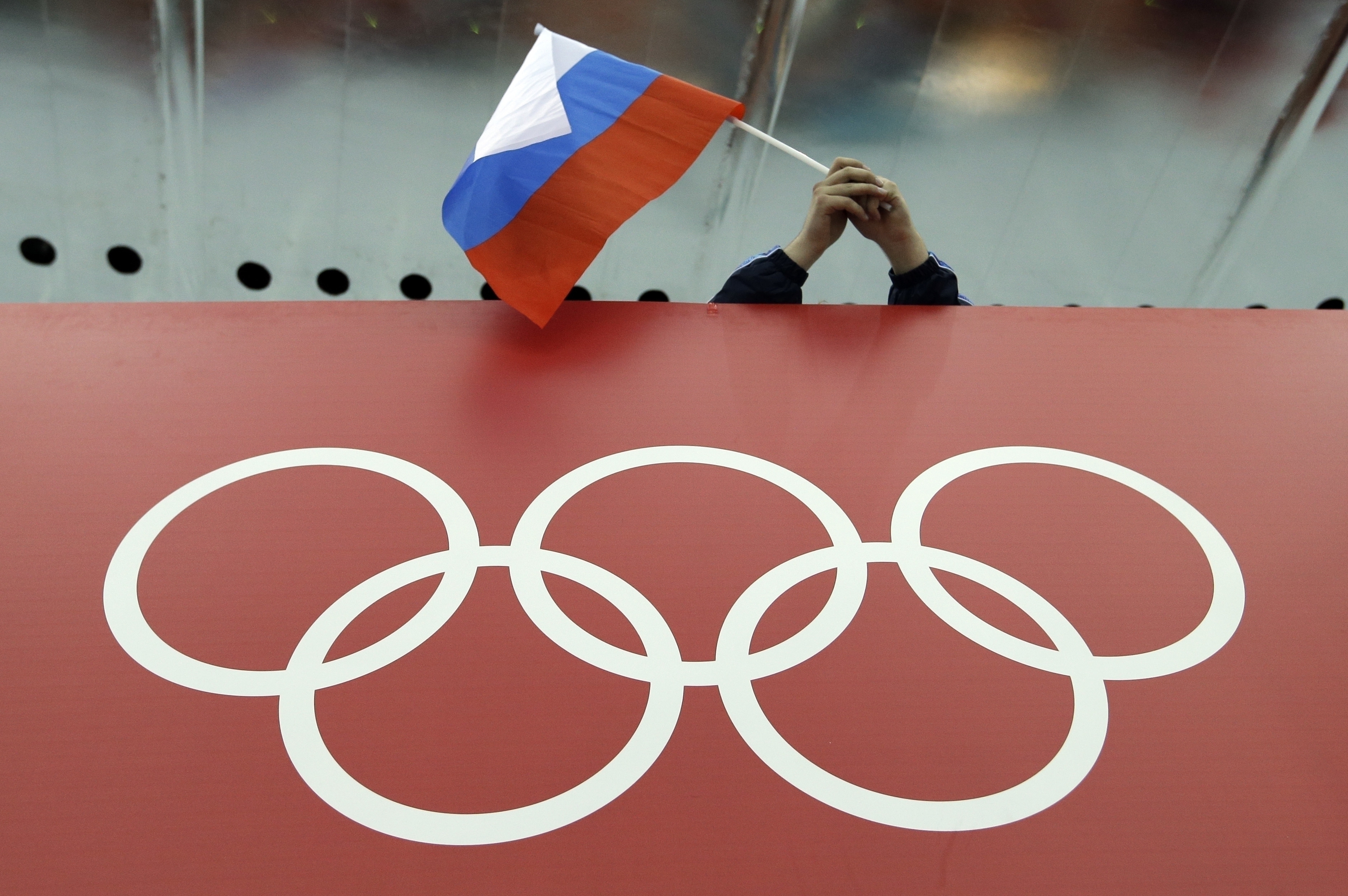 FILE - A Russian flag is held above the Olympic Rings at Adler Arena Skating Center during the Winter Olympics in Sochi, Russia on Feb. 18, 2014. Russia and its ally Belarus have been invited to compete at the Asian Games in the next step to qualify athletes for next year’s Paris Olympics. The arrangement has been brokered by the International Olympic Committee. The IOC indicated on Wednesday that it favours allowing Russians to compete at the 2024 Olympics as neutral athletes. 