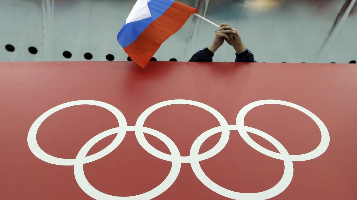 FILE - A Russian flag is held above the Olympic Rings at Adler Arena Skating Center during the Winter Olympics in Sochi, Russia on Feb. 18, 2014. Russia and its ally Belarus have been invited to compete at the Asian Games in the next step to qualify athletes for next year’s Paris Olympics. The arrangement has been brokered by the International Olympic Committee. The IOC indicated on Wednesday that it favours allowing Russians to compete at the 2024 Olympics as neutral athletes.