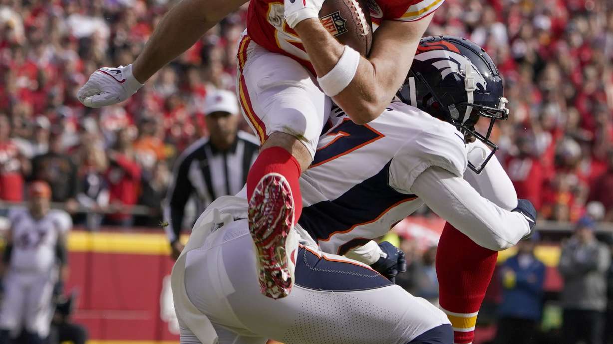 Kansas City Chiefs tight end Travis Kelce (87) leaps over Denver Broncos cornerback Damarri Mathis after catching a pass during the first half of an NFL football game Sunday, Jan. 1, 2023, in Kansas City, Mo.