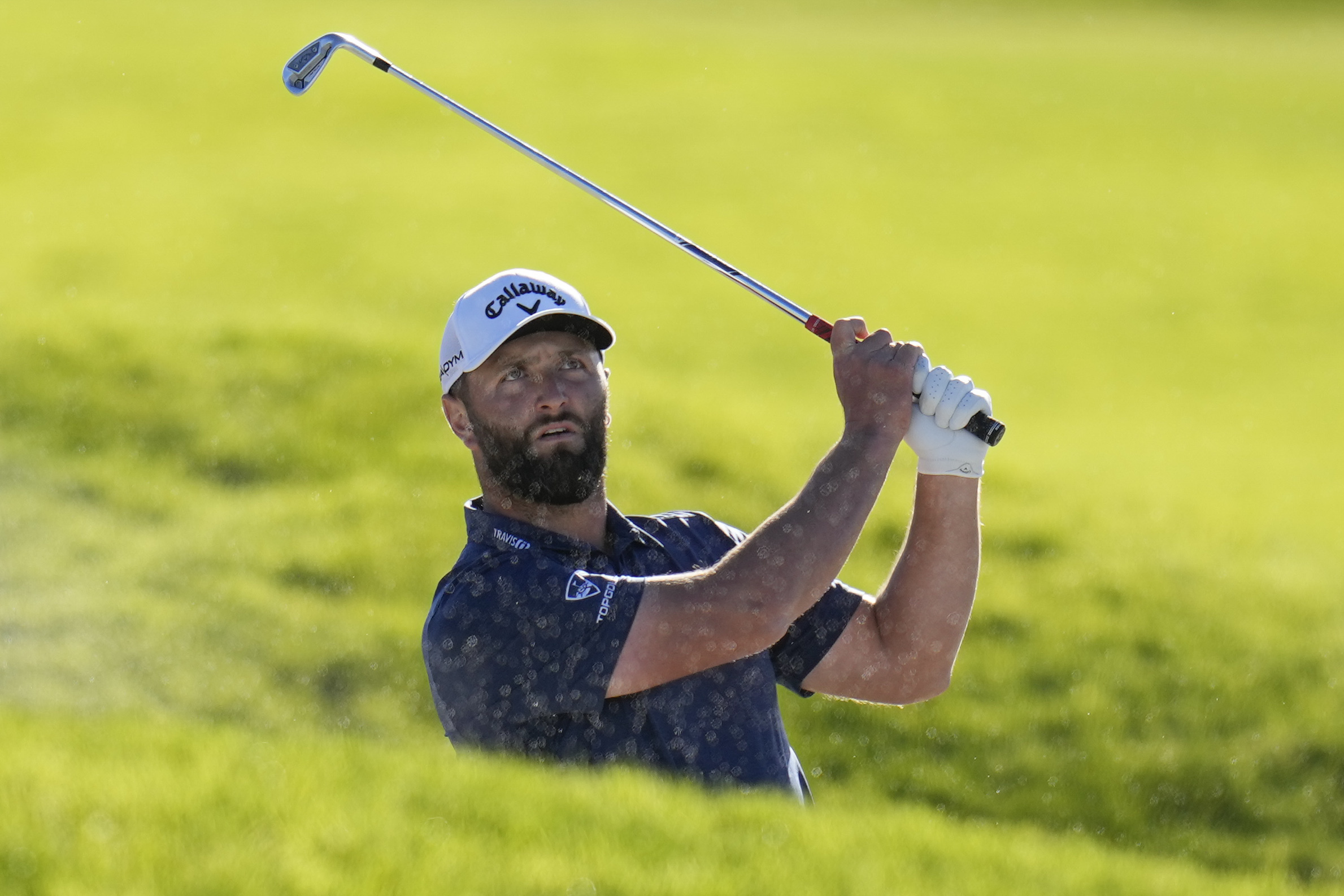 Jon Rahm, of Spain, watches after hitting out of a bunker on the 17th hole of the South Course at Torrey Pines during the third round of the Farmers Insurance Open golf tournament, Friday, Jan. 27, 2023, in San Diego. 