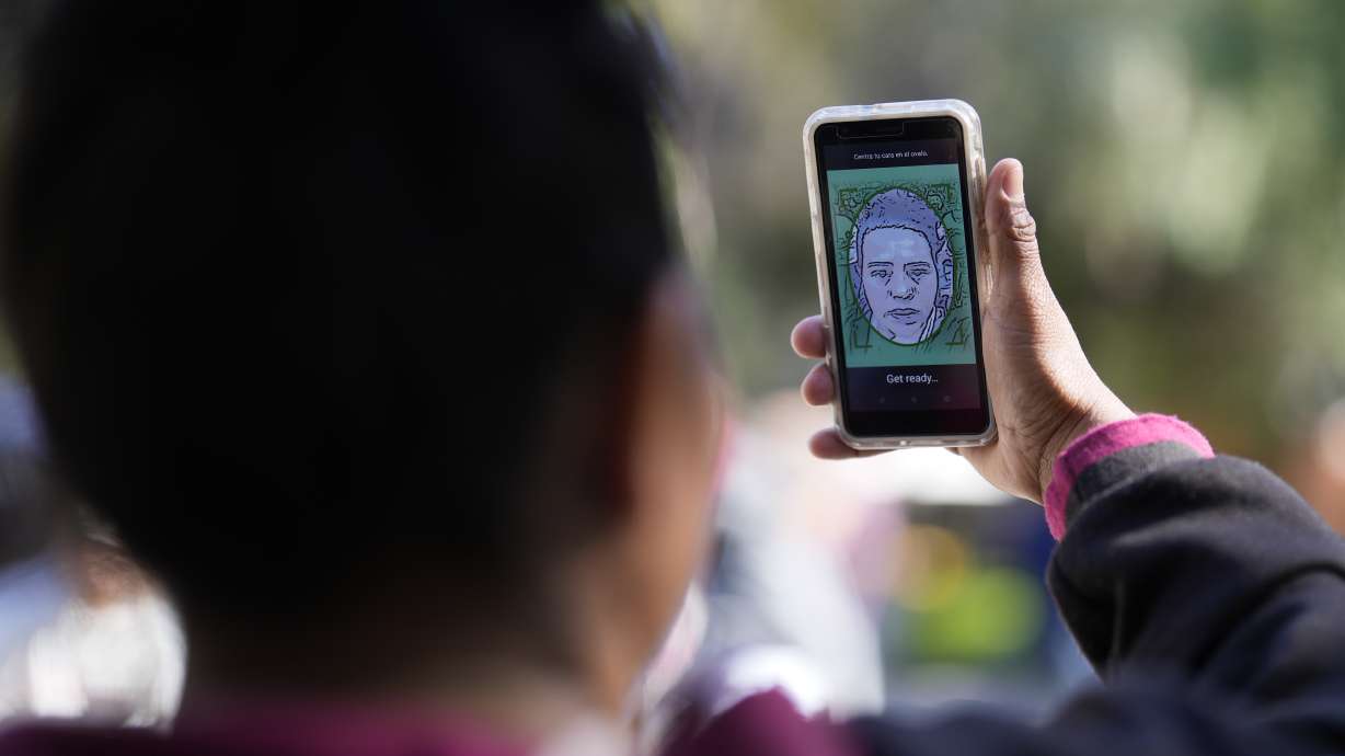 A migrant from Michoacan, Mexico, uses the CBPOne app Tuesday, in Tijuana, Mexico. A mobile app for migrants to seek asylum in the United States has been overwhelmed since it was introduced this month.