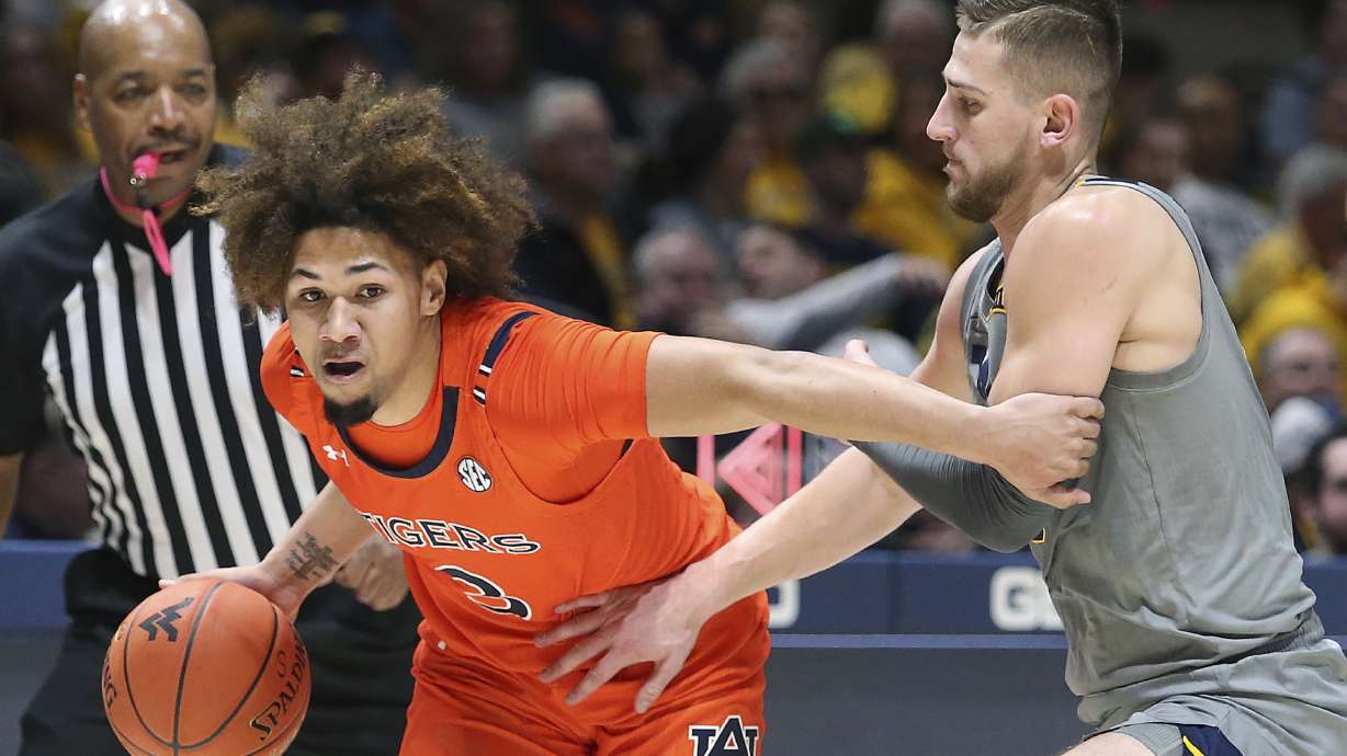 Auburn guard Tre Donaldson (3) is defended by West Virginia guard Erik Stevenson during the first half of an NCAA college basketball game on Saturday, Jan. 28, 2023, in Morgantown, W.Va.