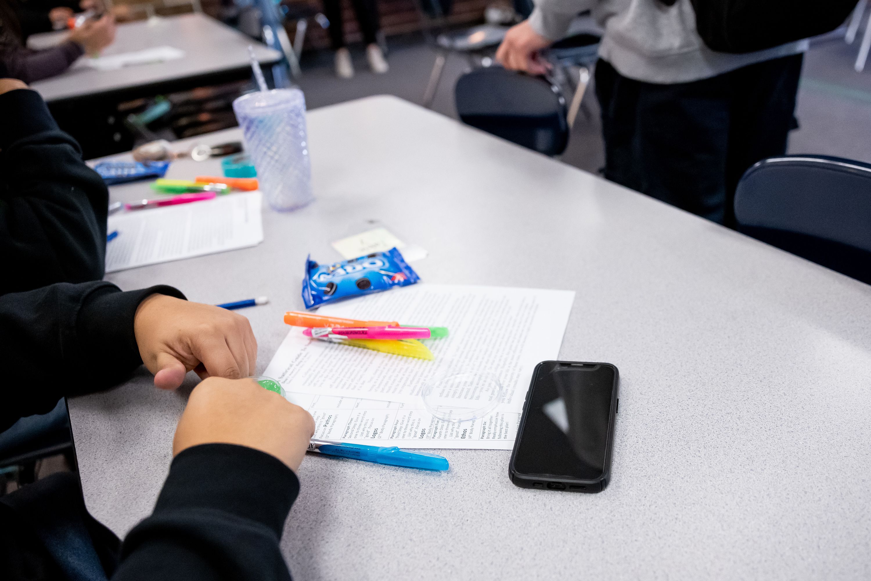 A student has their cellphone out on a table as their class begins at Cyprus High School in Magna on Friday.The school’s policy allows for cellphones and other electronic devices to be used between classes, but they must be put away during class.