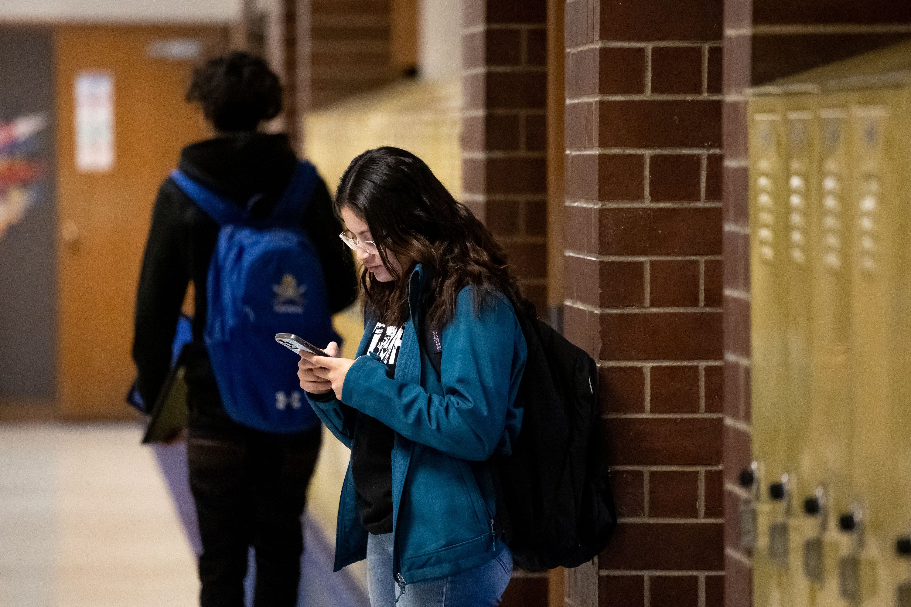 Sarah Valle, 17, uses her phone between classes at Cyprus High School in Magna on Friday. The school’s policy allows for cellphones and other electronic devices to be used between classes, but they must be put away during class.