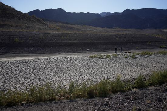 People walk by cracked earth in an area once under the water of Lake Mead at the Lake Mead National Recreation Area Jan. 27 near Boulder City, Nev. Competing priorities, outsized demands and the federal government's retreat from a threatened deadline all combined to thwart a voluntary deal last summer on how to drastically cut water use from the parched Colorado River, according to emails obtained by the Associated Press.