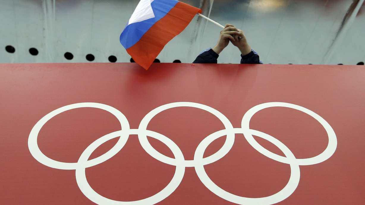 A Russian flag is held above the Olympic Rings at Adler Arena Skating Center during the Winter Olympics in Sochi, Russia, on Feb. 18, 2014. The International Olympic Committee’s plans to let some Russians compete at the 2024 Paris Summer Games is drawing reaction on all sides.