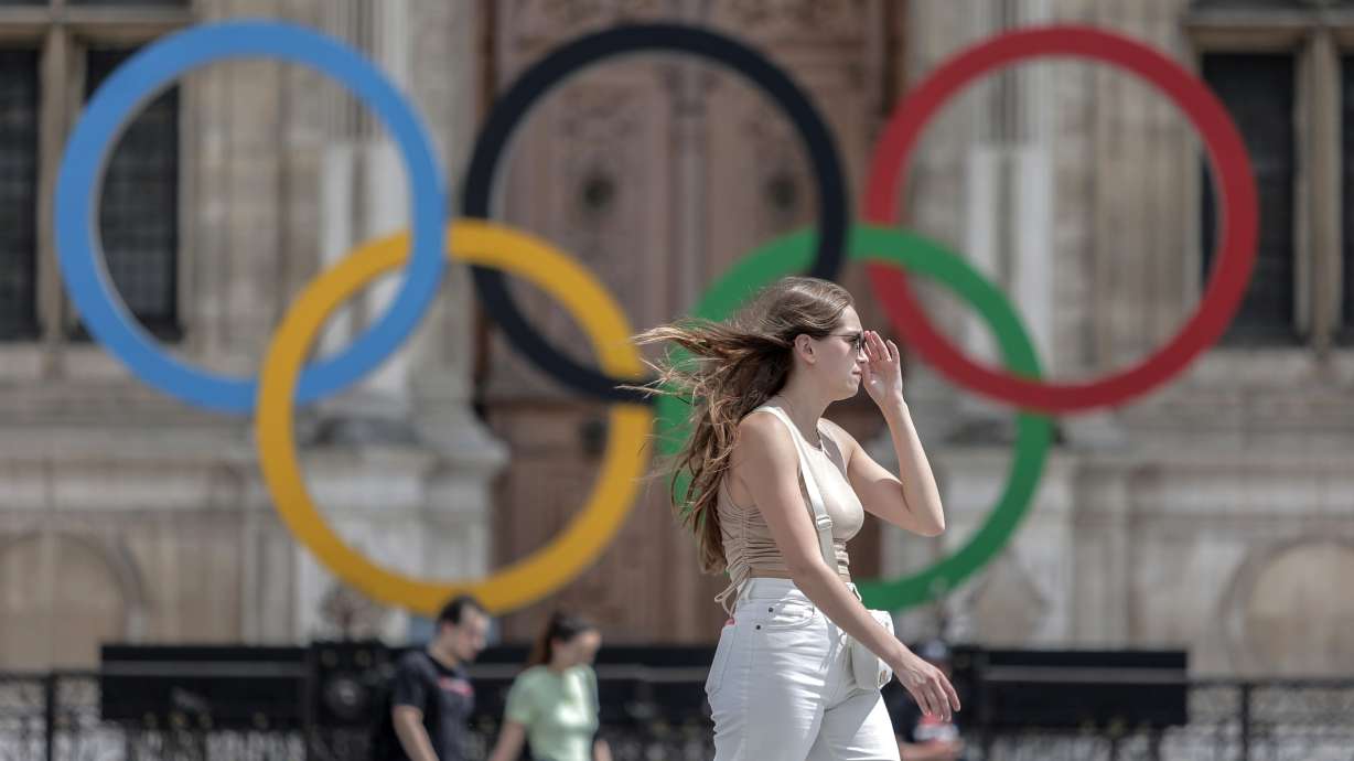 FILE - A woman passes by the Olympic rings at the City Hall in Paris, on July 25, 2022. Latvia is threatening to boycott next year’s Paris Olympics if athletes from Russia and its ally Belarus are allowed to take part after Russia's invasion of Ukraine.