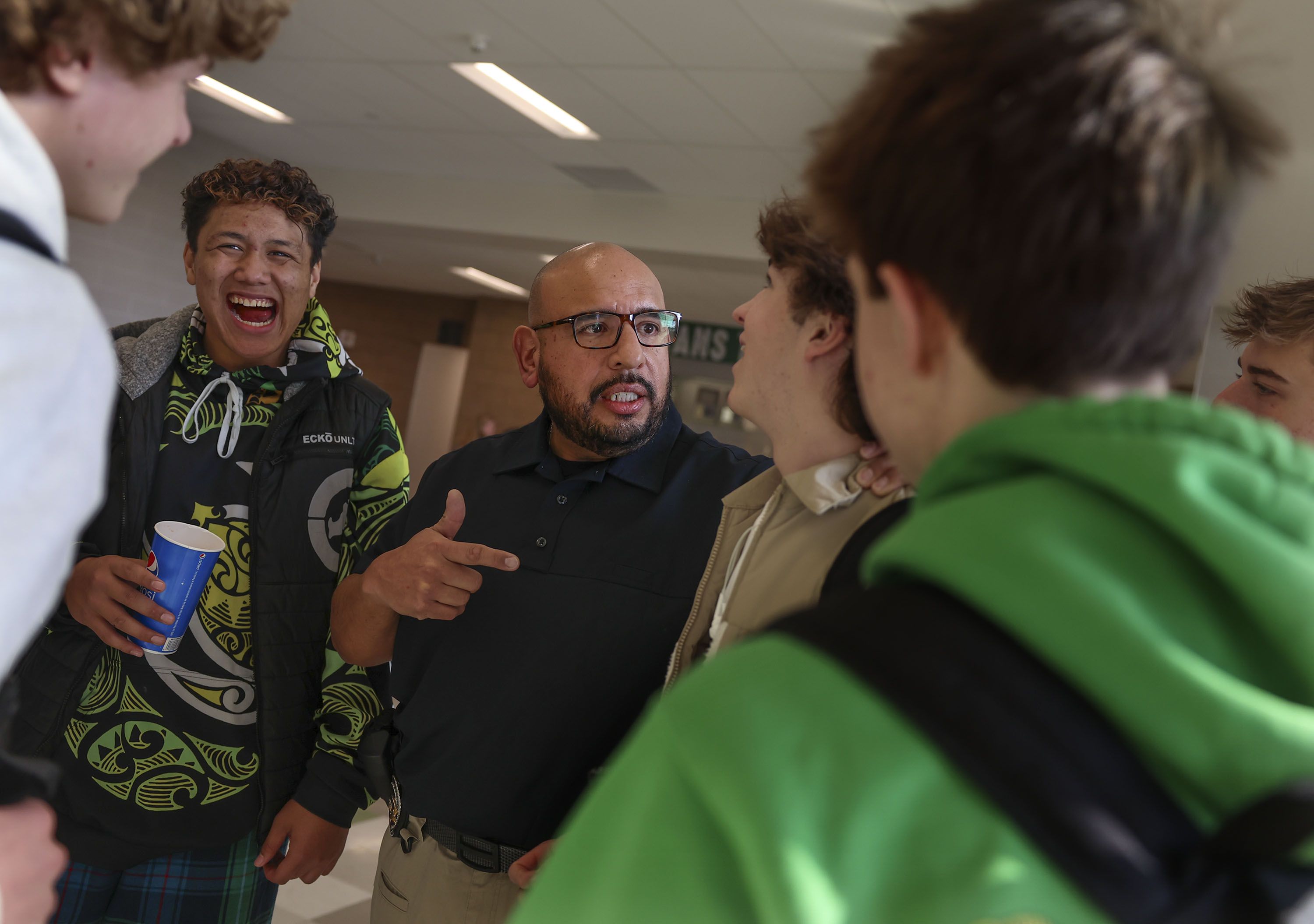 Unified Police SRO Detective Jaime Cardenas jokes around with students, including Akeli Naea, left and Cade Felts, right, at Olympus High School in Holladay on Thursday. Cardenas has been an SRO, a sworn law enforcement officer responsible for safety and crime prevention in schools, at Olympus High for four years.