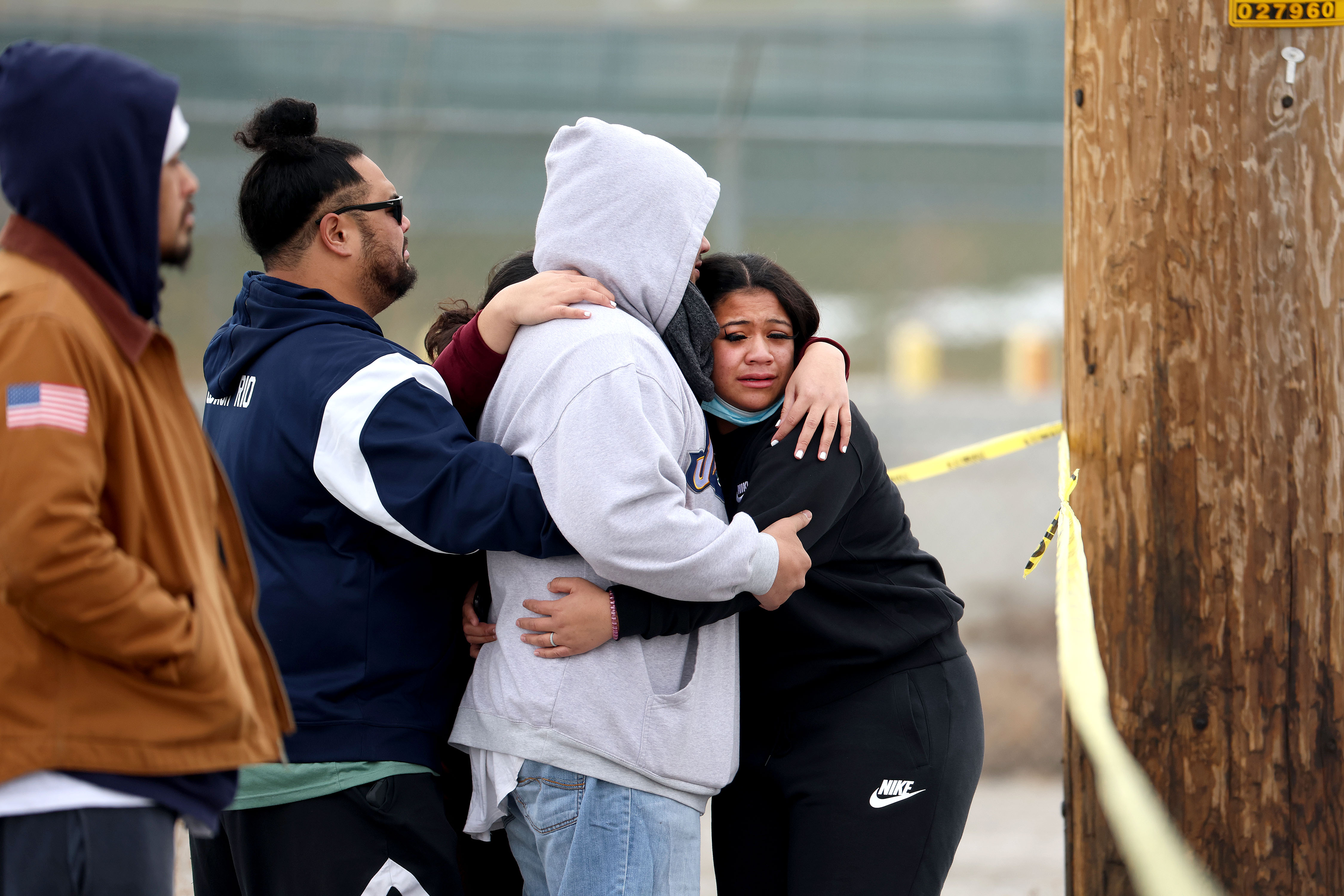 People comfort each other as they gather near the scene as police investigate a fatal shooting in West Valley City near Hunter High School on Jan. 13, 2022.