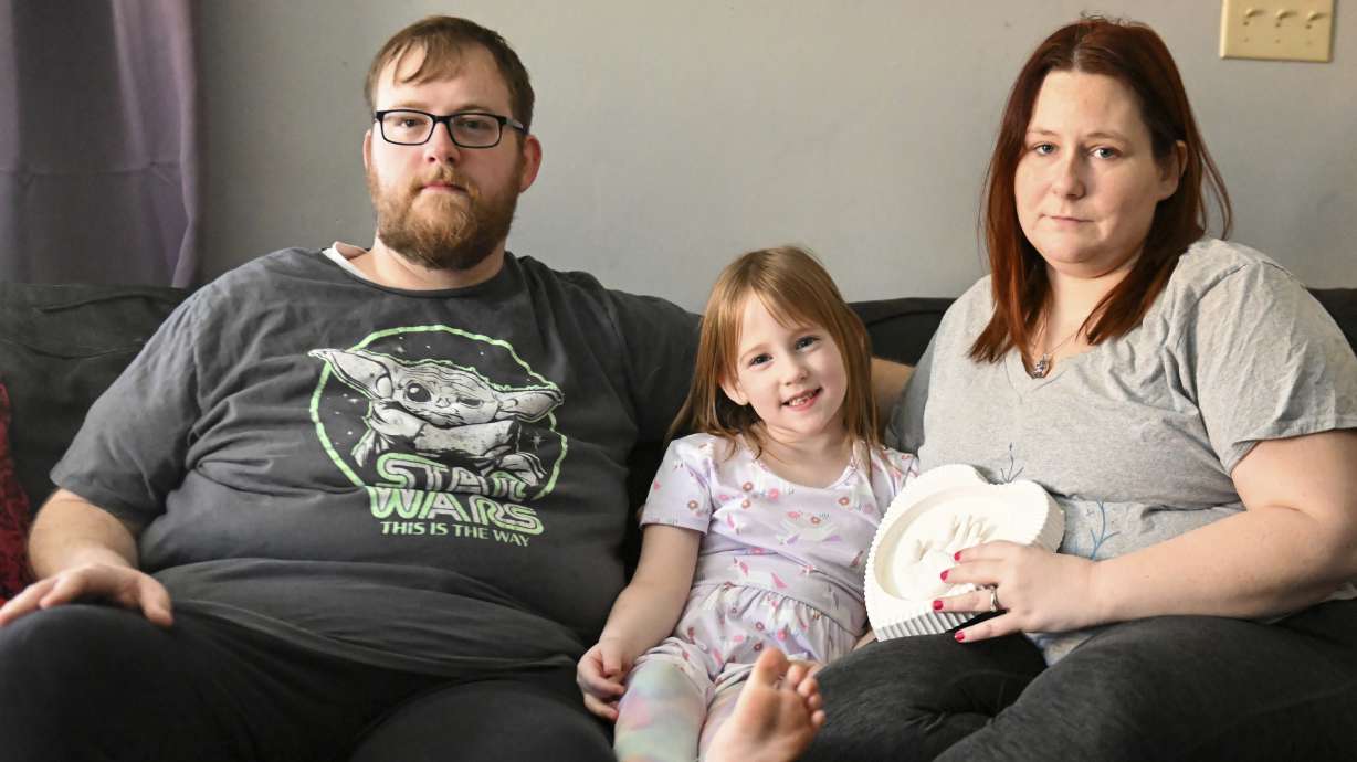 Andrew Weaver, from left, Caitlin Weaver and Jessica Day-Weaver hold a ceramic hand print of daughter, Anastasia, at their home, Thursday, in Boardman, Ohio. Results from the 6-year-old's autopsy may take weeks. But online anti-vaccine activists needed only hours after her funeral this week to baselessly blame the COVID-19 vaccine.