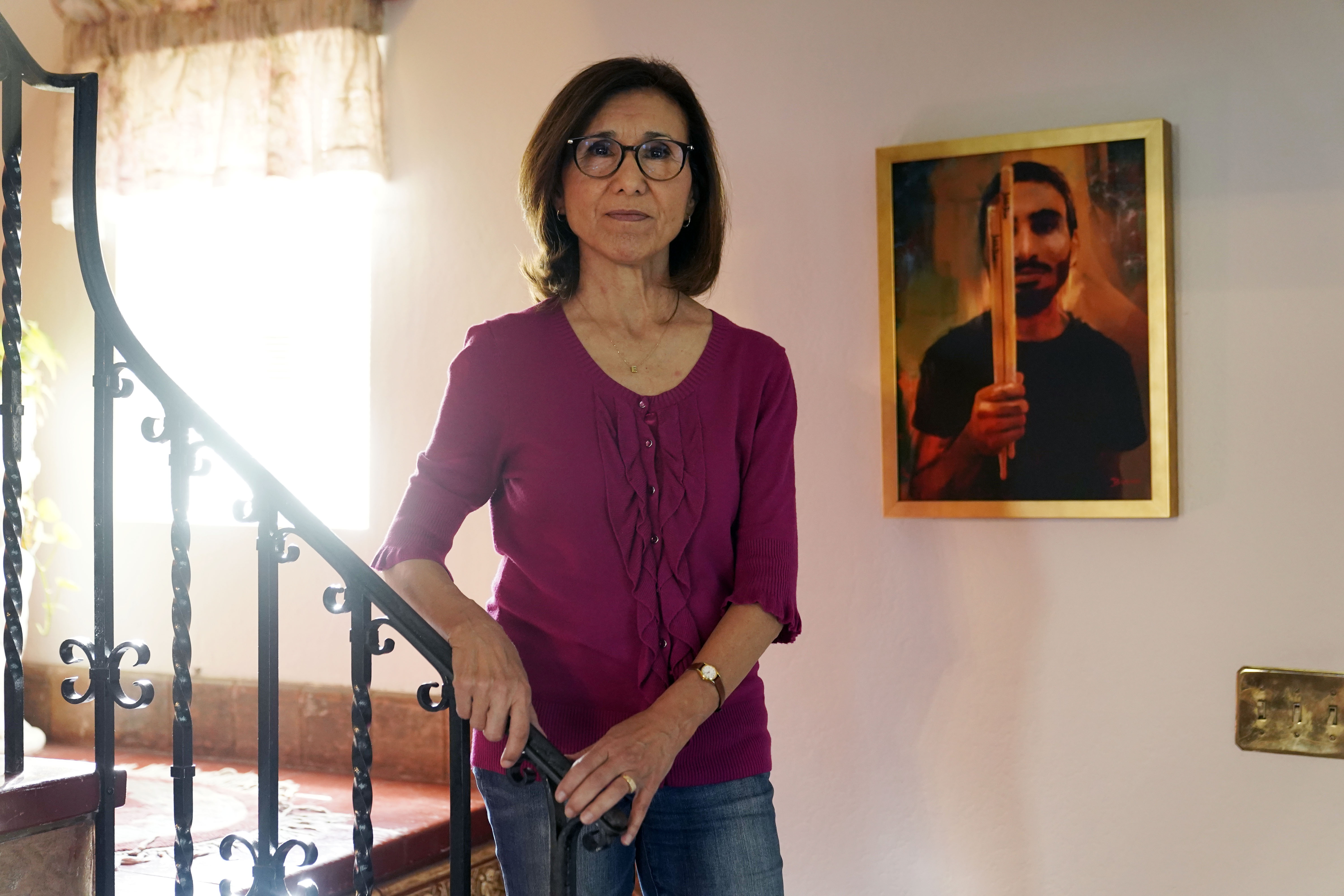 Dolores Cruz poses next to a painting of her youngest son, Eric Cruz, on Wednesday at her home in San Gabriel, Califirbua. Cruz published an essay in 2022 about grieving for her son, who died in a car crash in 2017. "Died Suddenly" used a screenshot of the headline in the film, portraying his death as vaccine related.