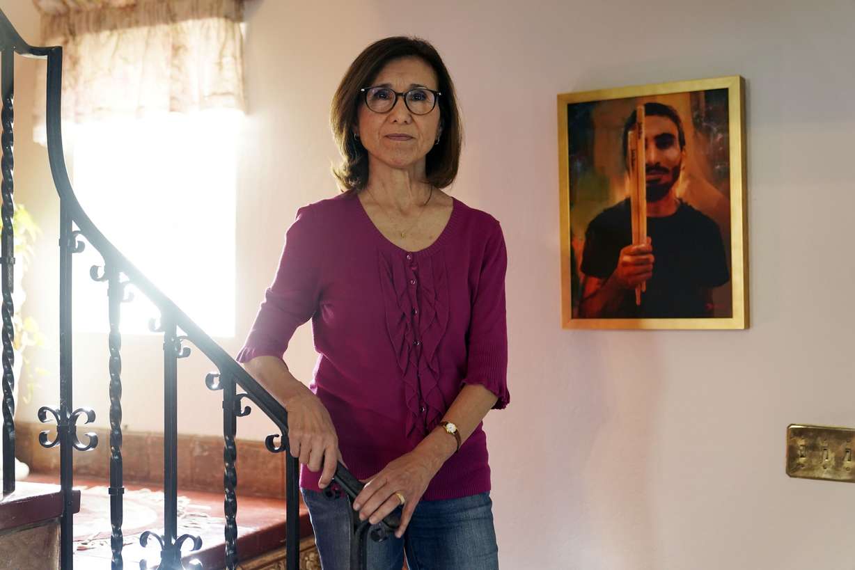 Dolores Cruz poses next to a painting of her youngest son, Eric Cruz, on Wednesday at her home in San Gabriel, Califirbua. Cruz published an essay in 2022 about grieving for her son, who died in a car crash in 2017. "Died Suddenly" used a screenshot of the headline in the film, portraying his death as vaccine related.