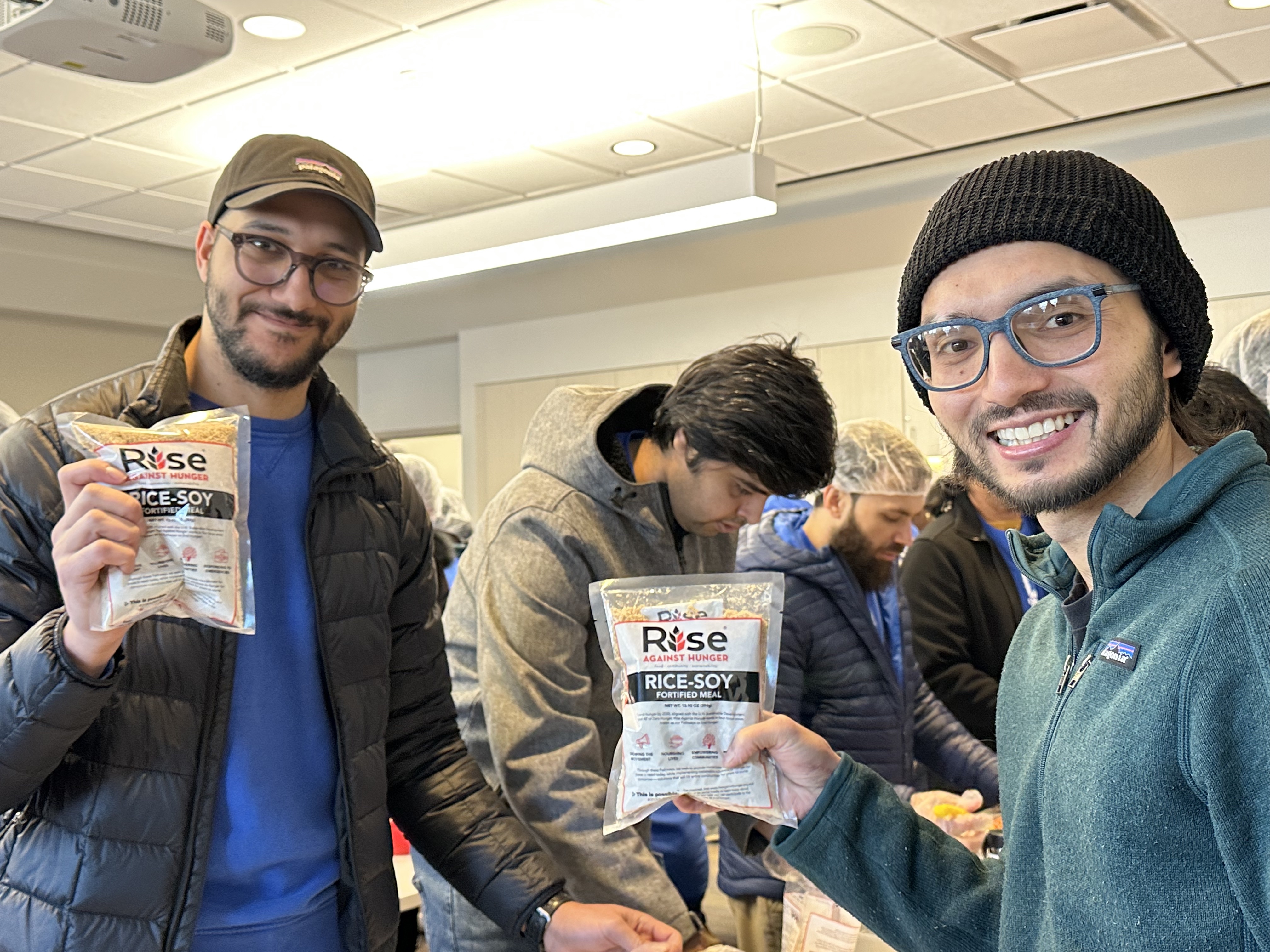 More than 80 people packed thousands of meals for those in need Saturday morning at the Bluffdale fire station.
Hisham Elsheshtawy and Amir Foy smile as they hold up a newly packaged meal.