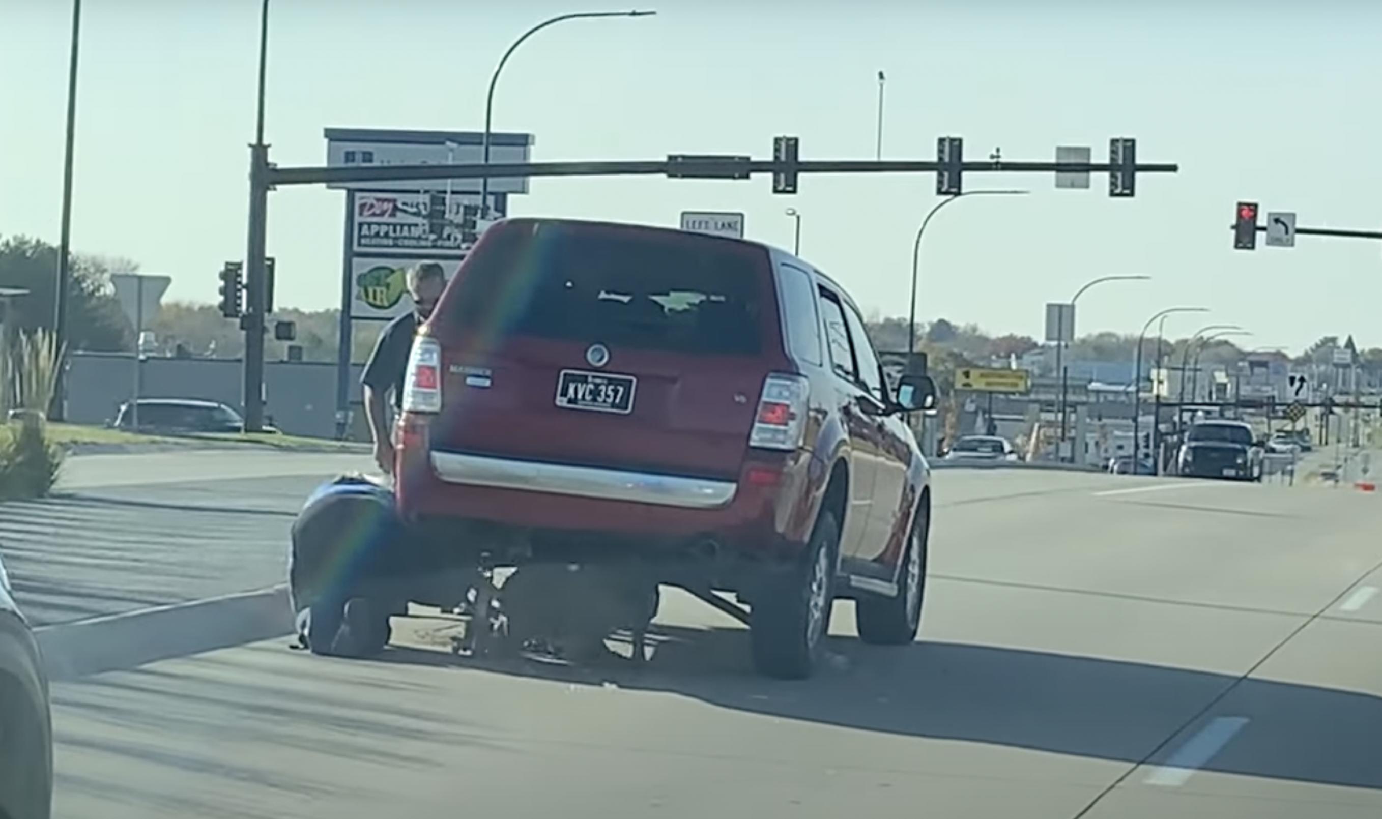 This image from an October 2022 video shows two good Samaritans helping to free a deer trapped underneath an SUV.