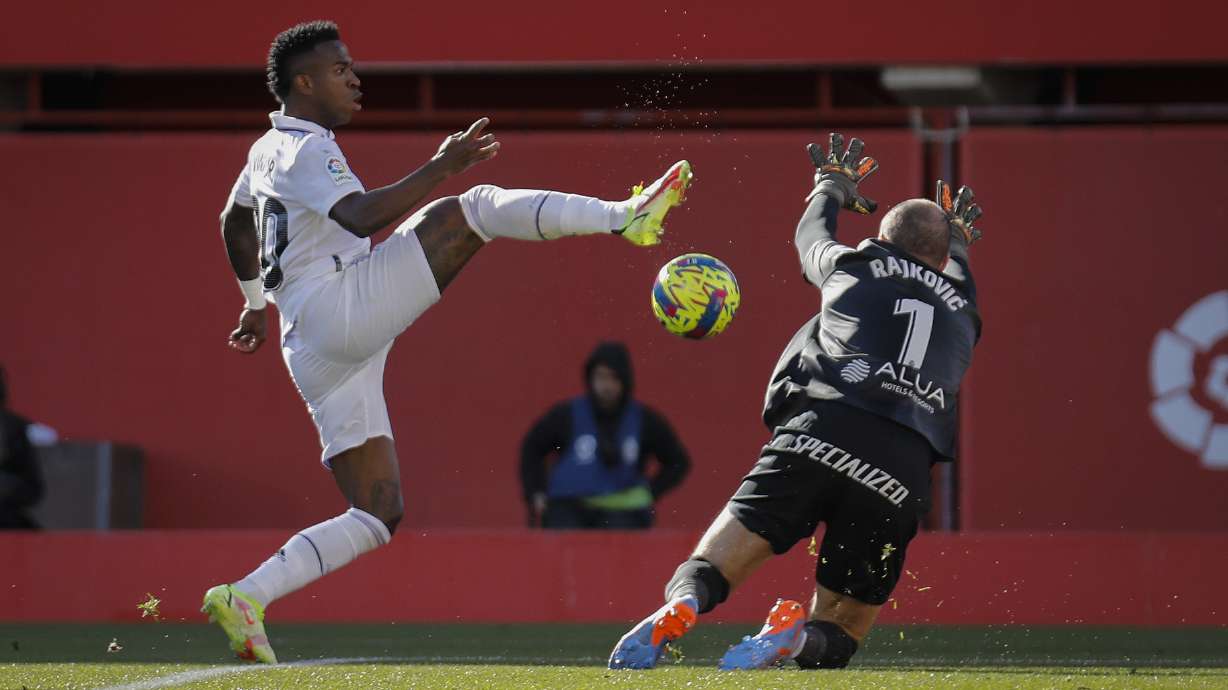 Real Madrid's Vinicius Junior, left, in action against Mallorca's goalkeeper Predrag Rajkovic during a Spanish La Liga soccer match between Mallorca and Real Madrid at the Son Moix stadium in Palma de Mallorca, Spain, Sunday, Feb. 5, 2023.