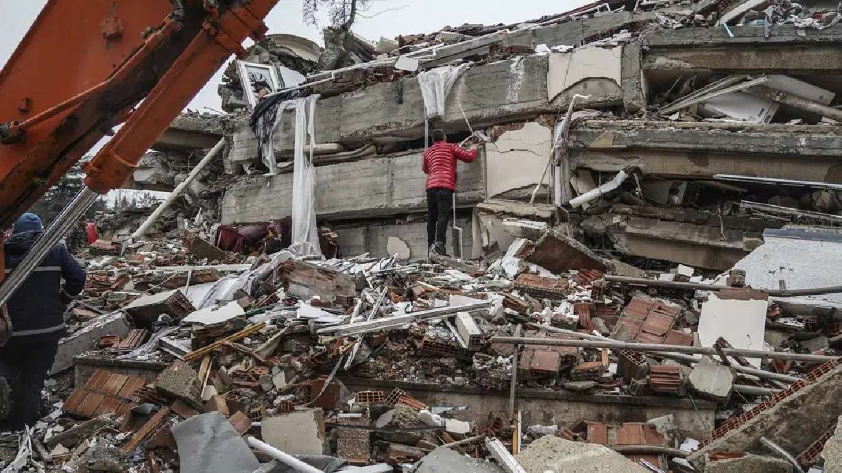 Men search for people among the debris in a destroyed building in Adana, Turkey, Monday. A powerful quake has knocked down multiple buildings in southeast Turkey and Syria and thousands were killed.