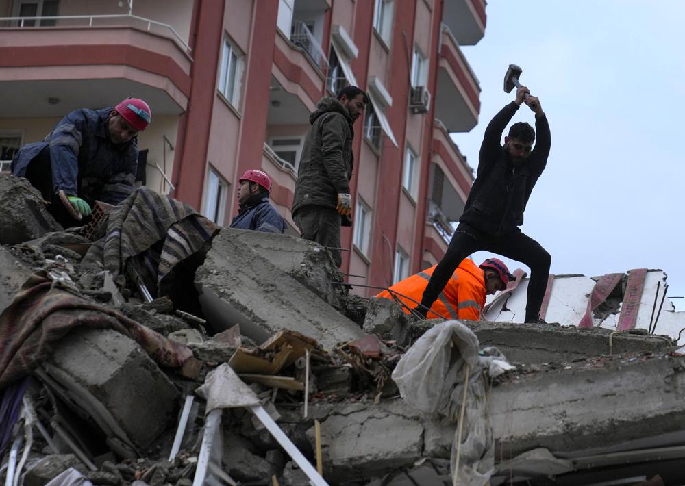 Emergency team members and others search for people in a destroyed building in Adana, Turkey, Monday. A powerful quake knocked down multiple buildings in southeast Turkey and Syria and thousands were killed.