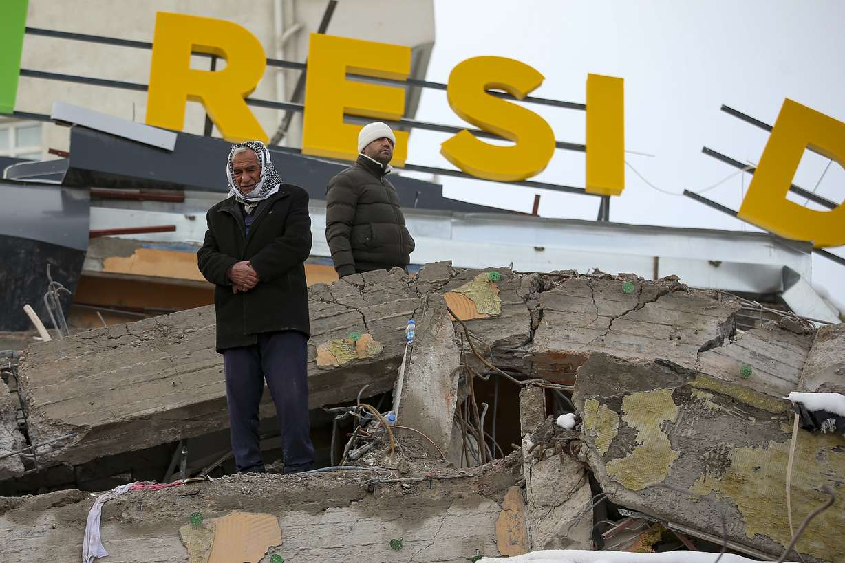 A man prays on a collapsed building in Malatya, Turkey, Tuesday. Search teams and aid are pouring into Turkey and Syria as rescuers working in freezing temperatures dig through the remains of buildings flattened by a magnitude 7.8 earthquake.