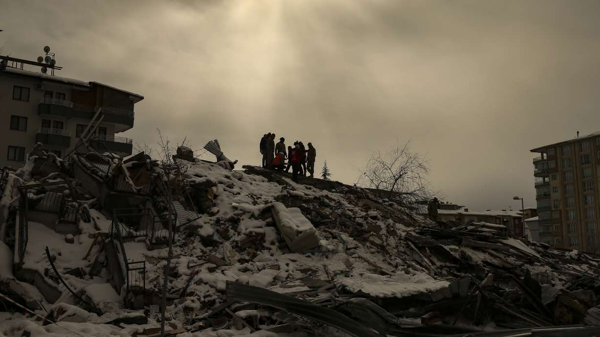 People try to reach people trapped under the debris of a collapsed building in Malatya, Turkey, Tuesday. Search teams and aid are pouring into Turkey and Syria as rescuers working in freezing temperatures dig through the remains of buildings flattened by a magnitude 7.8 earthquake.