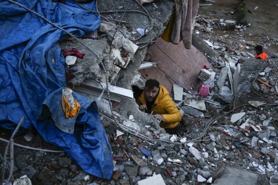 A man searches for people in a destroyed building in Adana, Turkey, Monday. A powerful quake has knocked down multiple buildings in southeast Turkey and Syria and many casualties are feared.