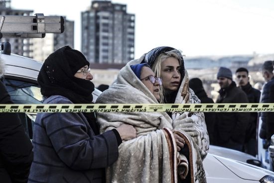 Three women watch the emergency teams as they search for survivors in the rubble of a destroyed building in Gaziantep, southeastern Turkey, Tuesday.