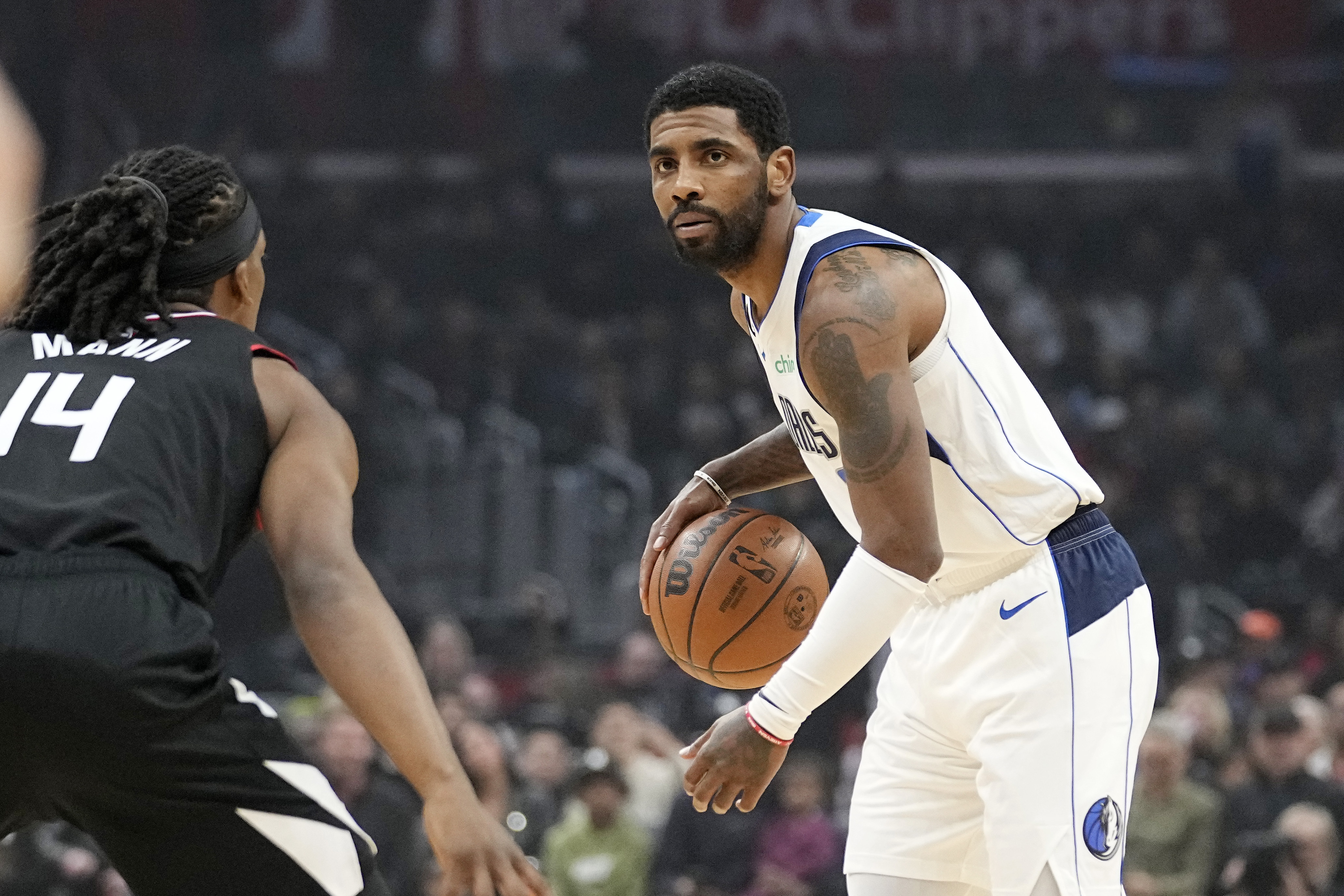 Dallas Mavericks guard Kyrie Irving, right, dribbles as Los Angeles Clippers guard Terance Mann defends during the first half of an NBA basketball game Wednesday, Feb. 8, 2023, in Los Angeles.